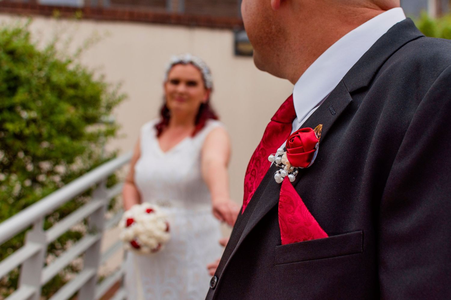 Wedding party members in formal attire with red accents walking outdoors.