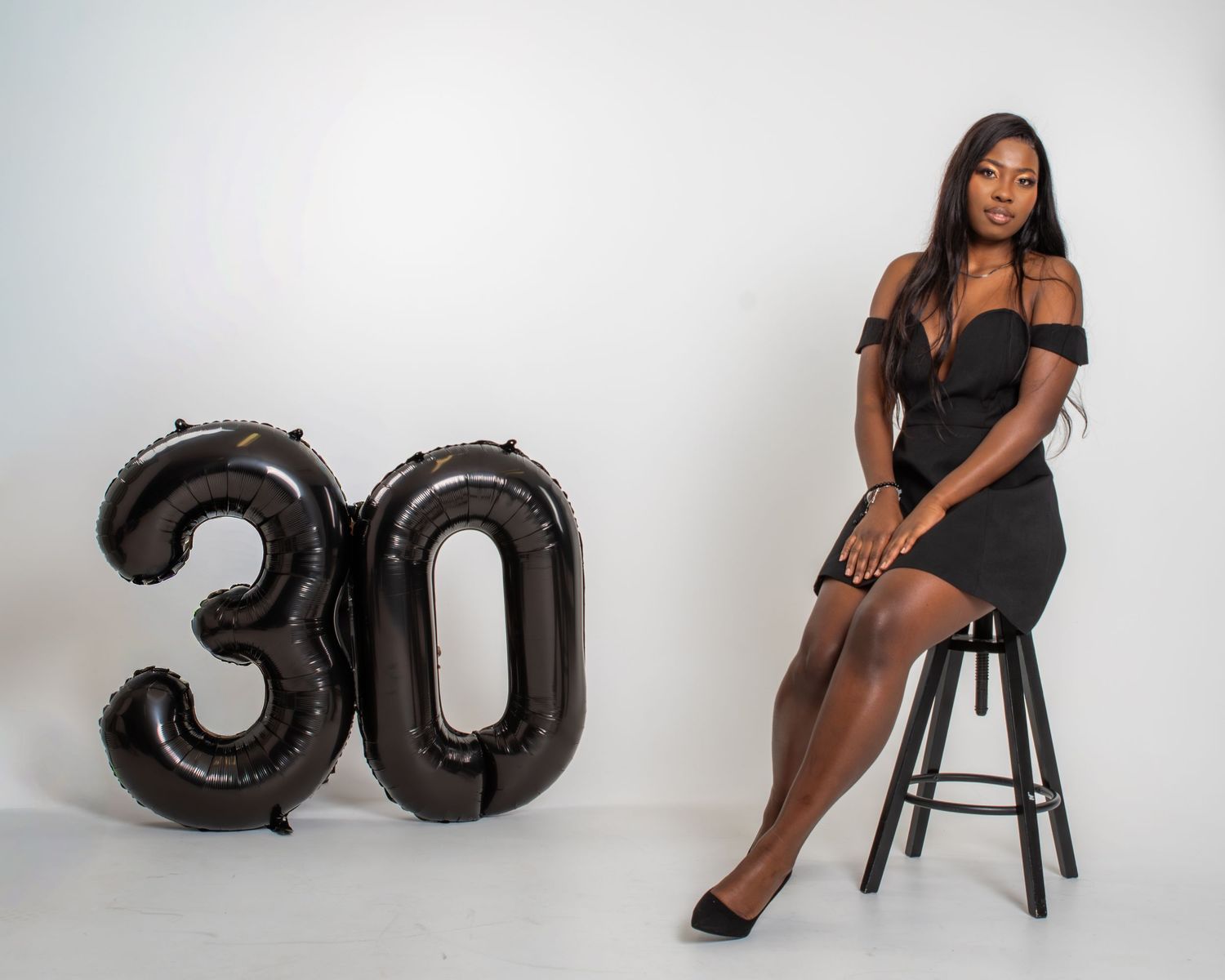 A series of glamorous birthday photoshoot images featuring black balloons shaped like numbers against a light background.