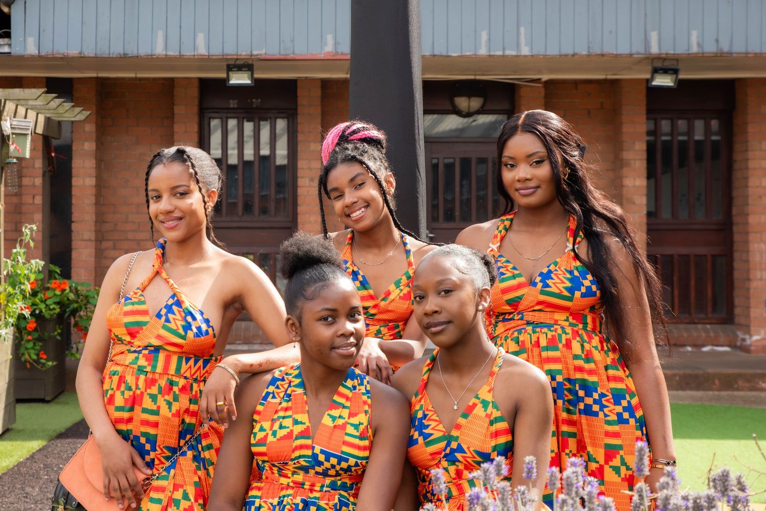Group wearing vibrant African print outfits posing together outdoors.