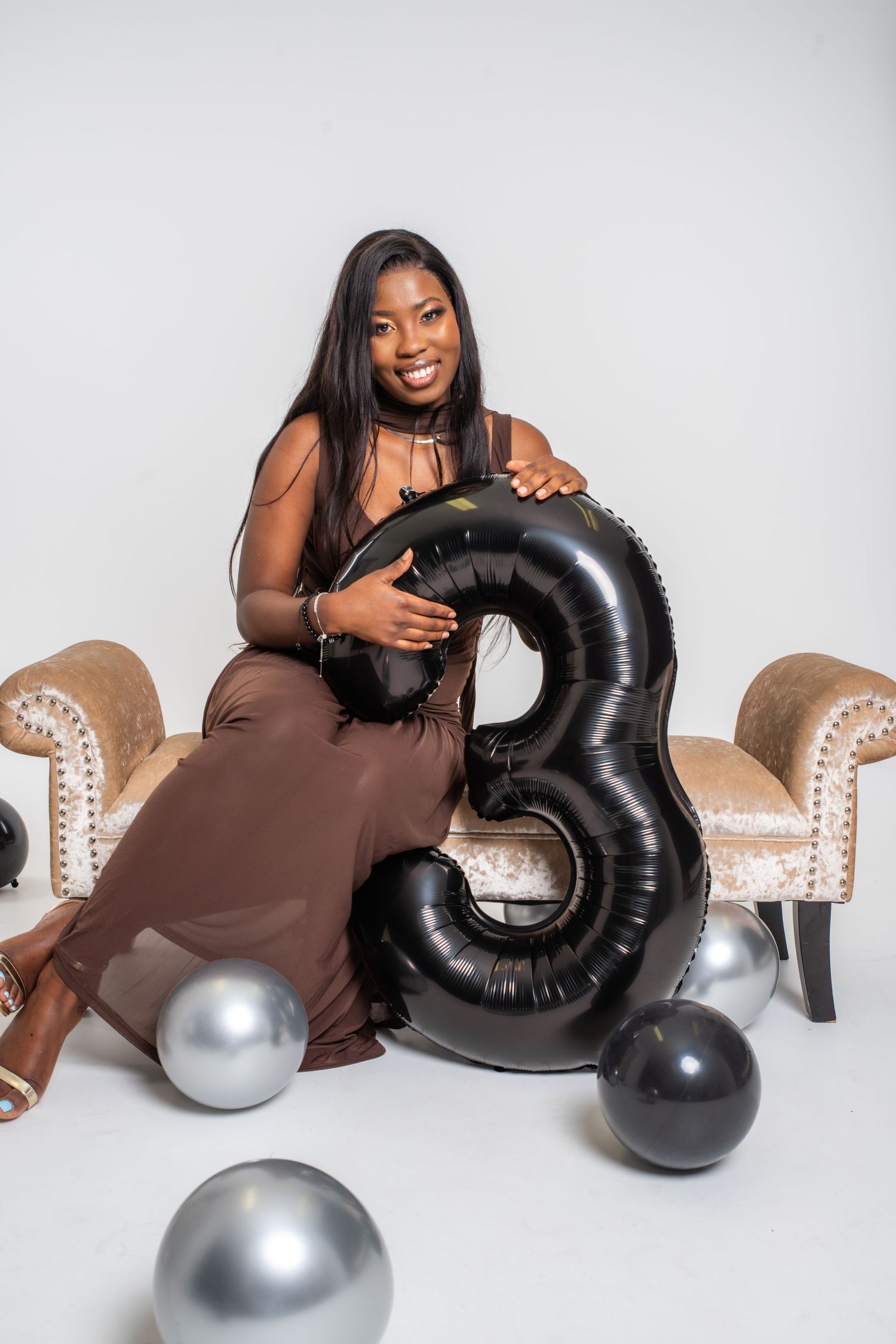 A series of four celebratory photos featuring large black and silver number balloon decorations against a white backdrop.