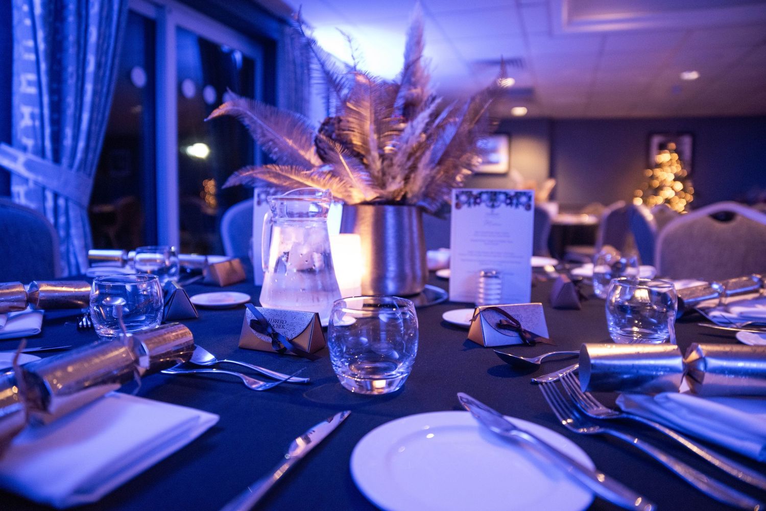 Elegant table settings with blue lighting and crystal glassware at formal event.