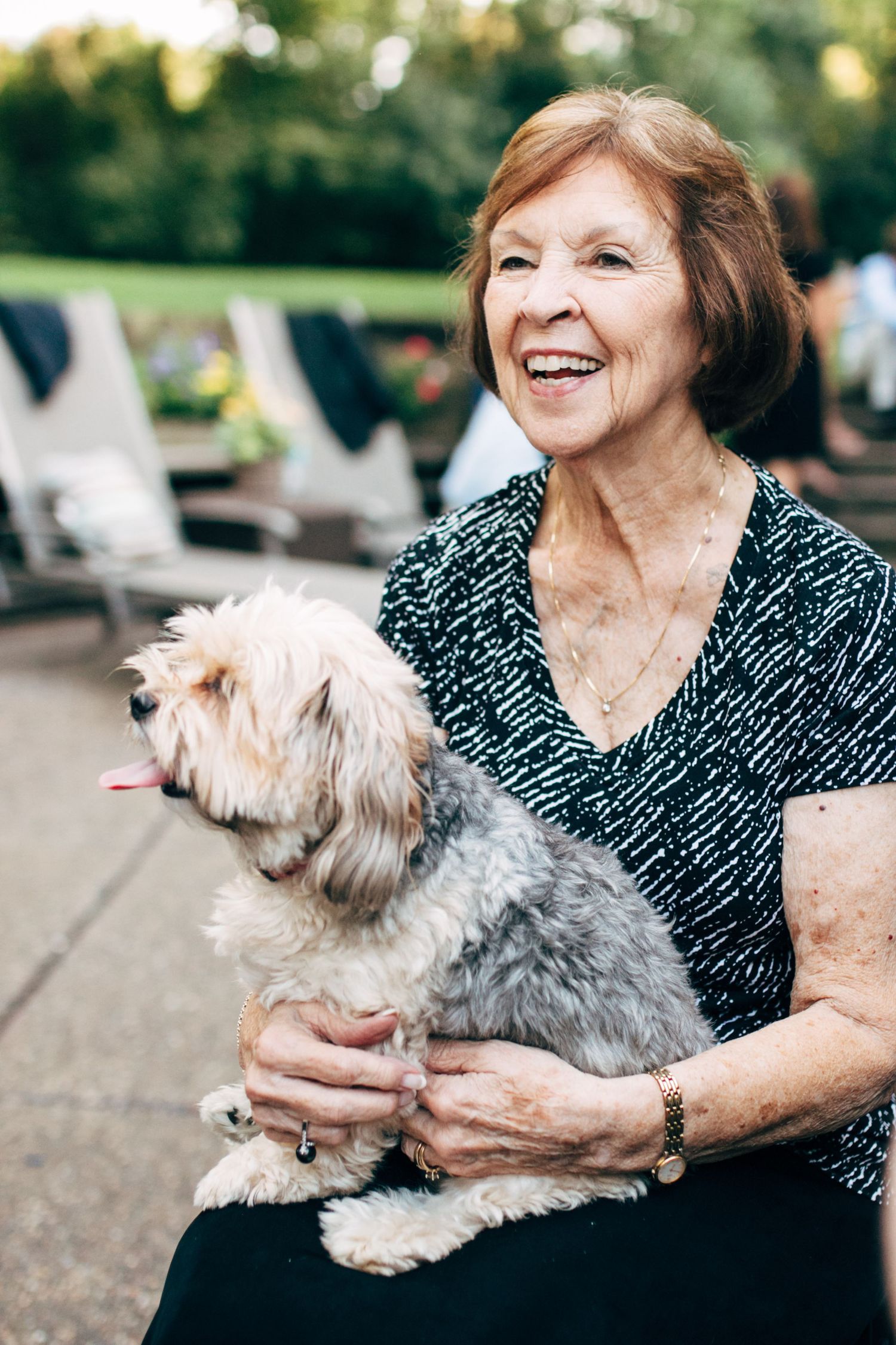 Person holding small fluffy white dog outdoors while smiling.