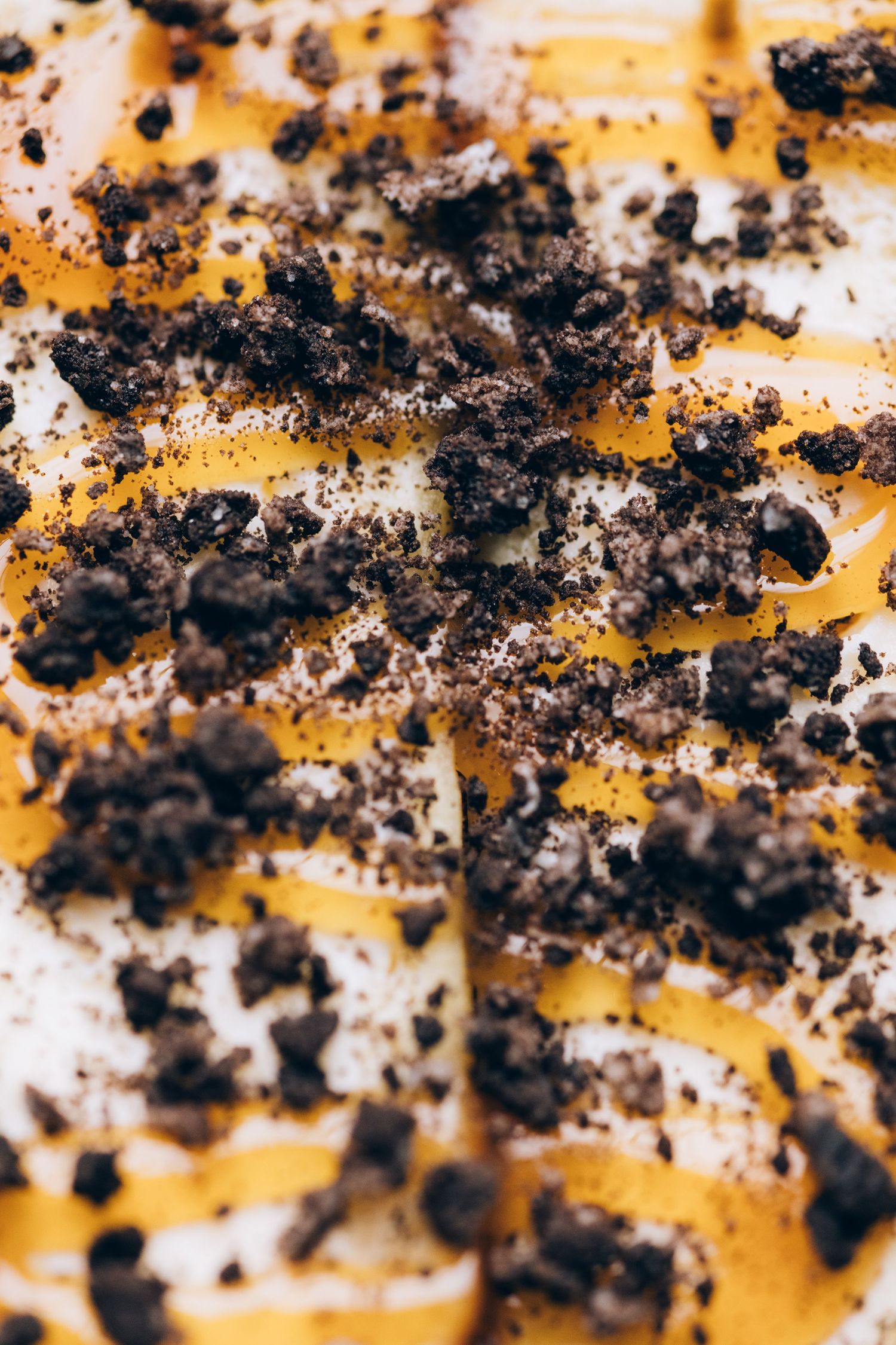 Macro shot of crushed Oreo cookie crumbs on orange surface.