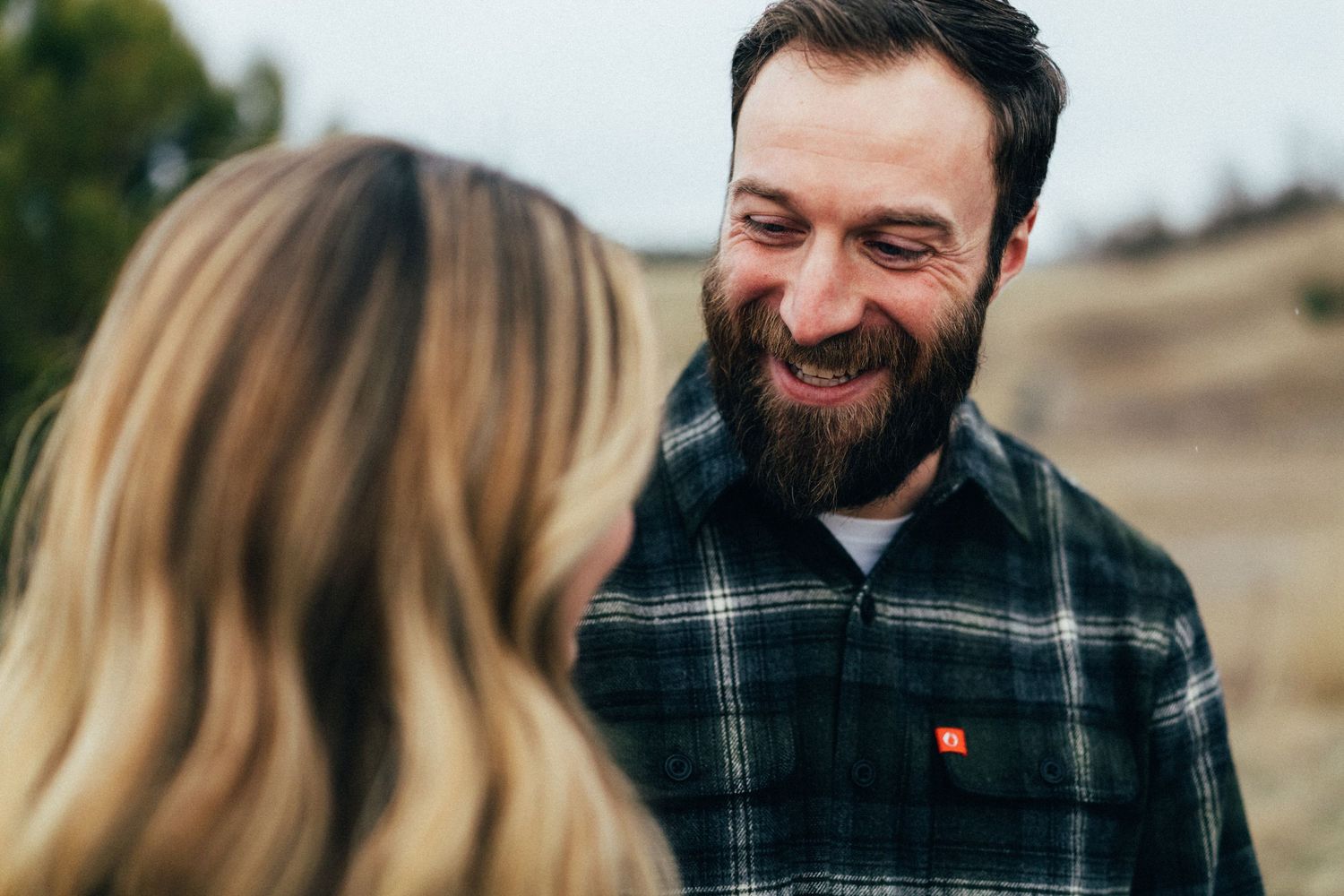 A candid moment of laughter between a couple wearing casual outdoor clothing.