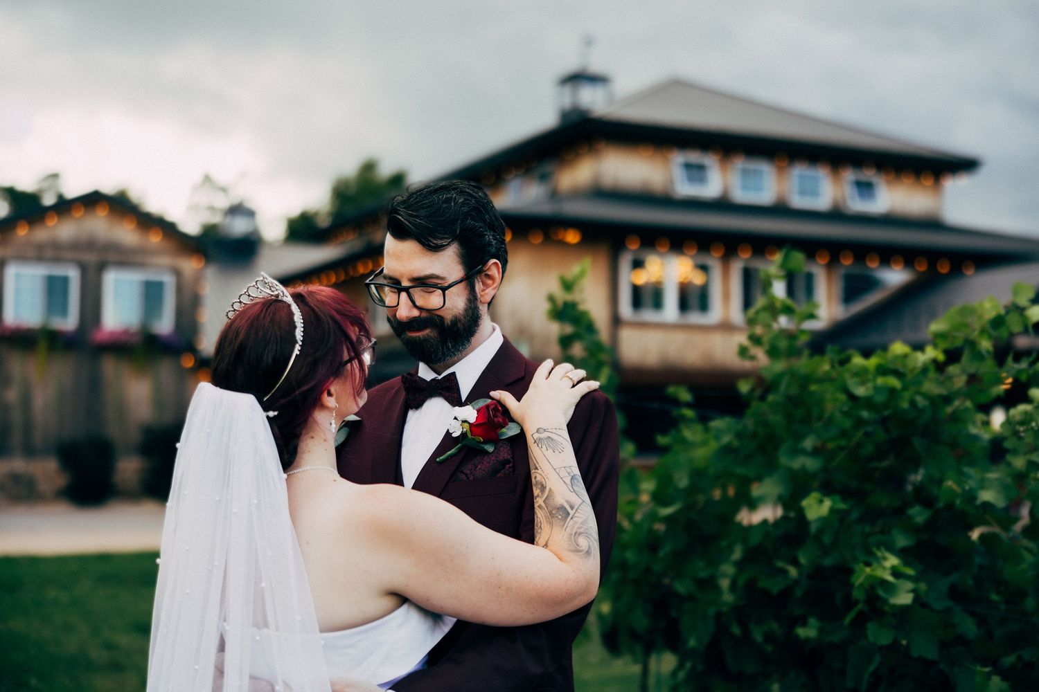 A bride and groom share a romantic moment outdoors near a vineyard venue on their wedding day.