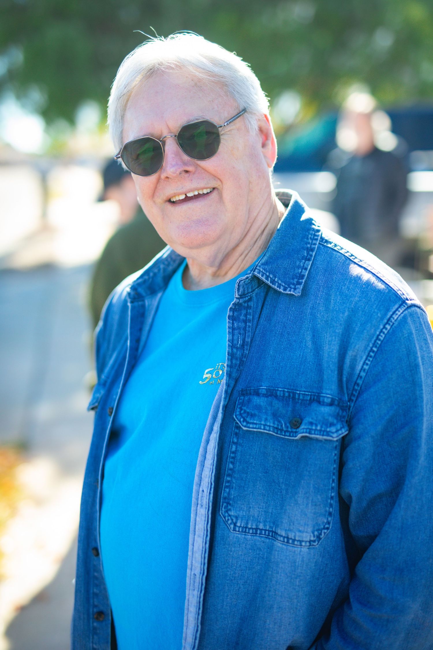 Casual outdoor portrait series featuring denim jacket and bright blue shirt in natural lighting.