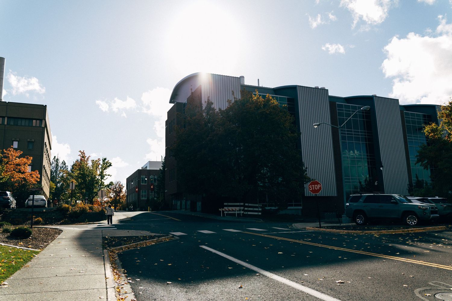 Modern buildings cast shadows under bright sunlight against a blue sky.