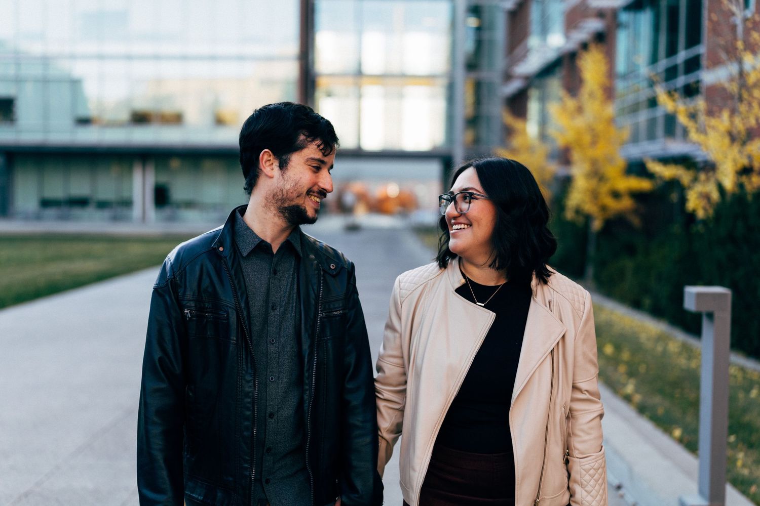 Couple sharing candid moments on walking path during autumn photoshoot.