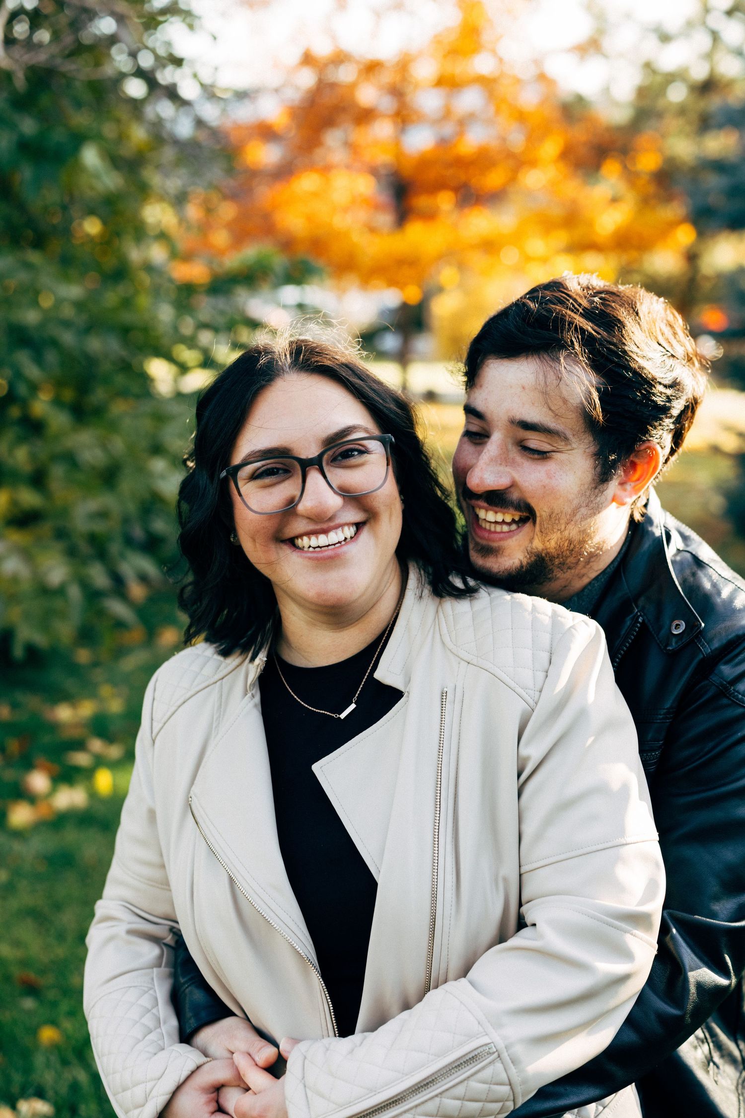 Couple sharing joyful laughter together outdoors with autumn colors in background.