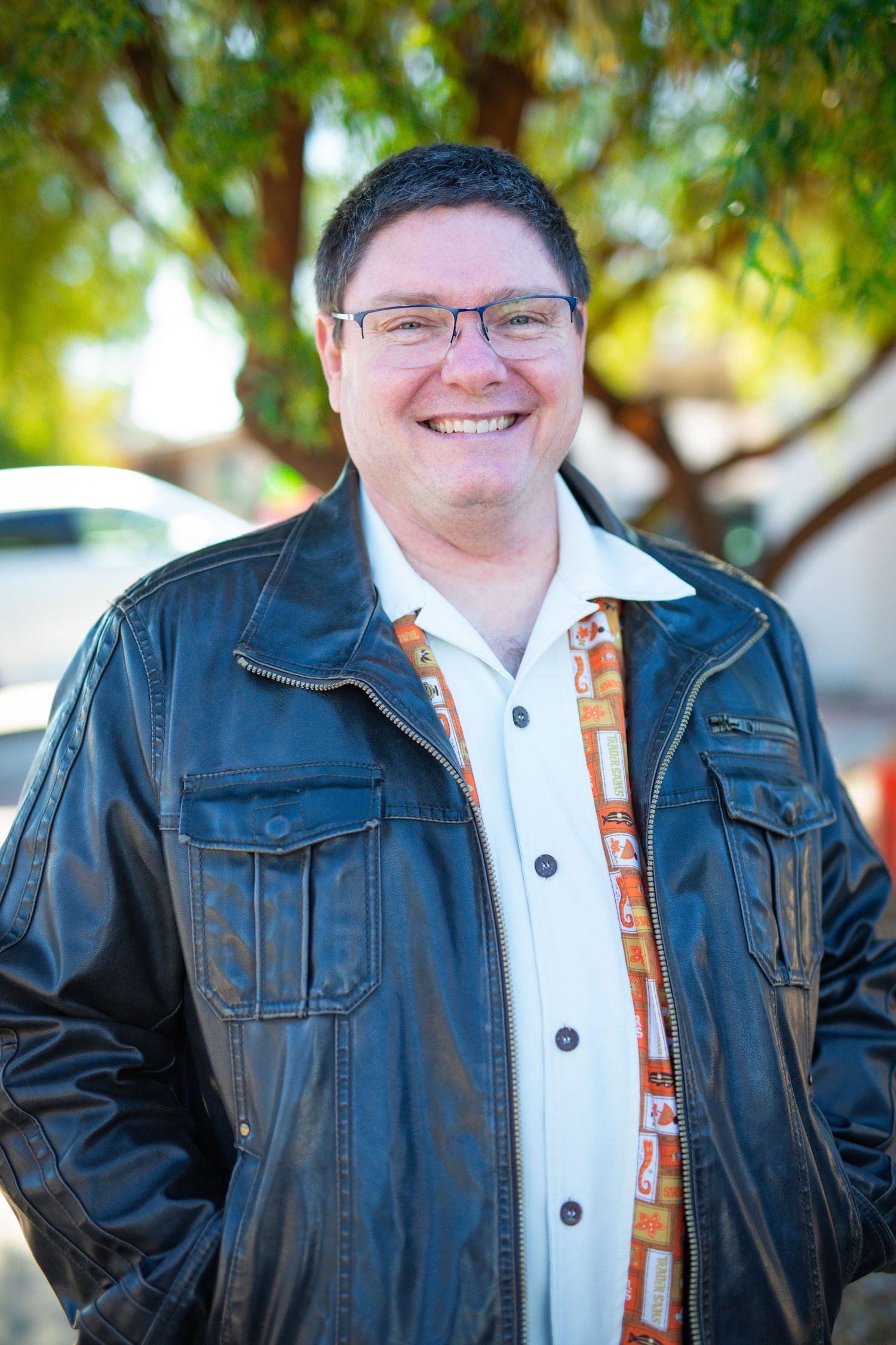 Portrait series showing person in black leather jacket and white polo shirt against leafy background.