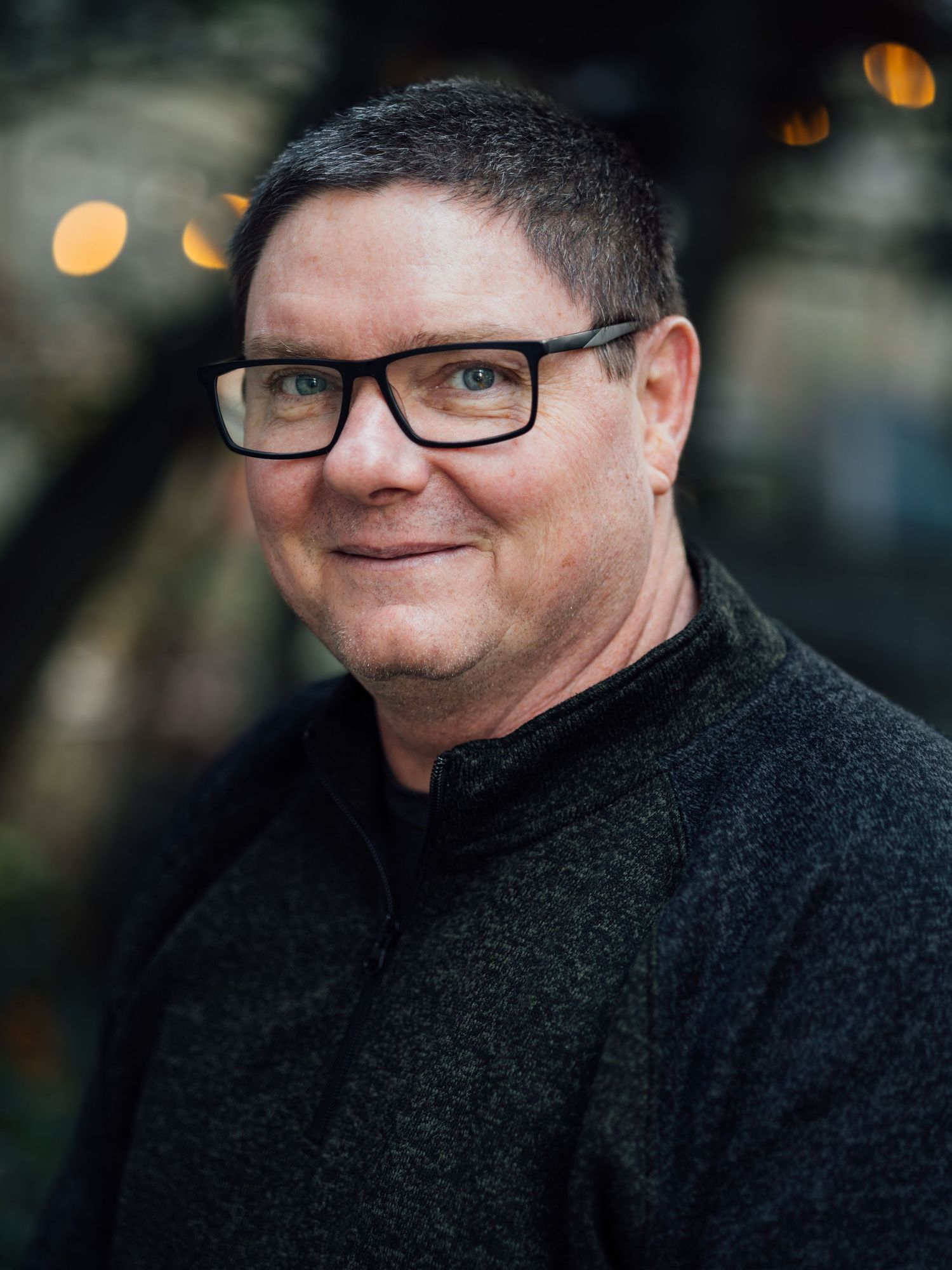 Close-up portrait series showing expressions in black sweater against dark background.