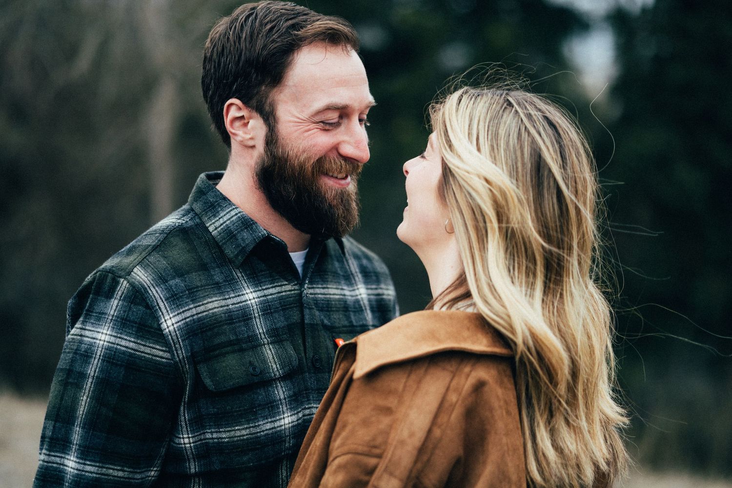 A couple sharing a joyful moment together while wearing flannel and suede outdoors.