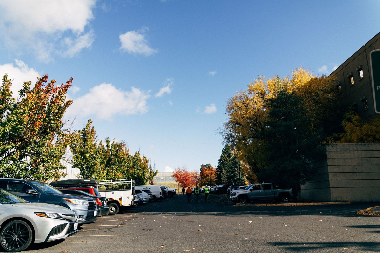 Parking lot surrounded by autumn trees with colorful foliage on a clear day.