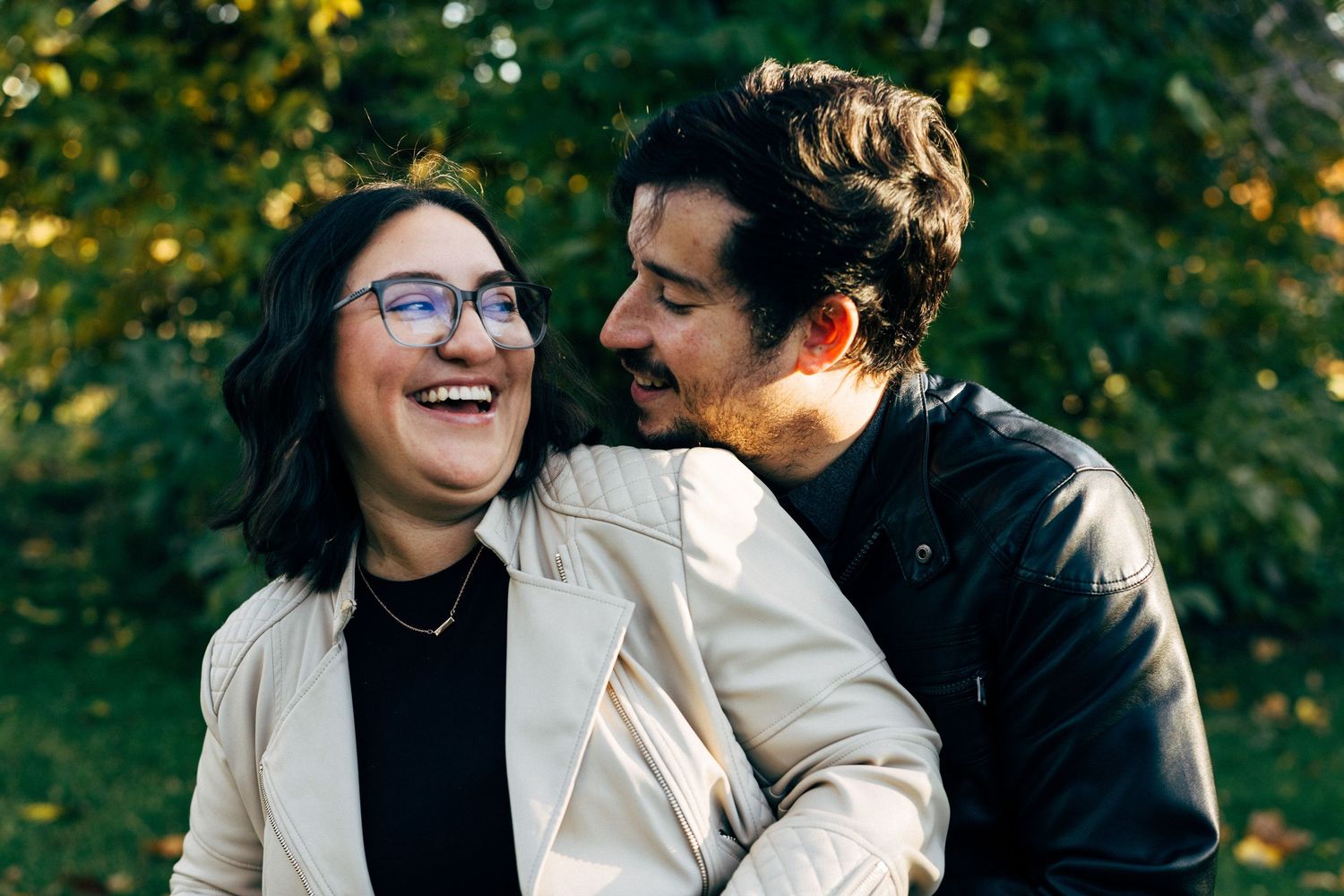 Couple sharing intimate moments during outdoor photoshoot with natural greenery.