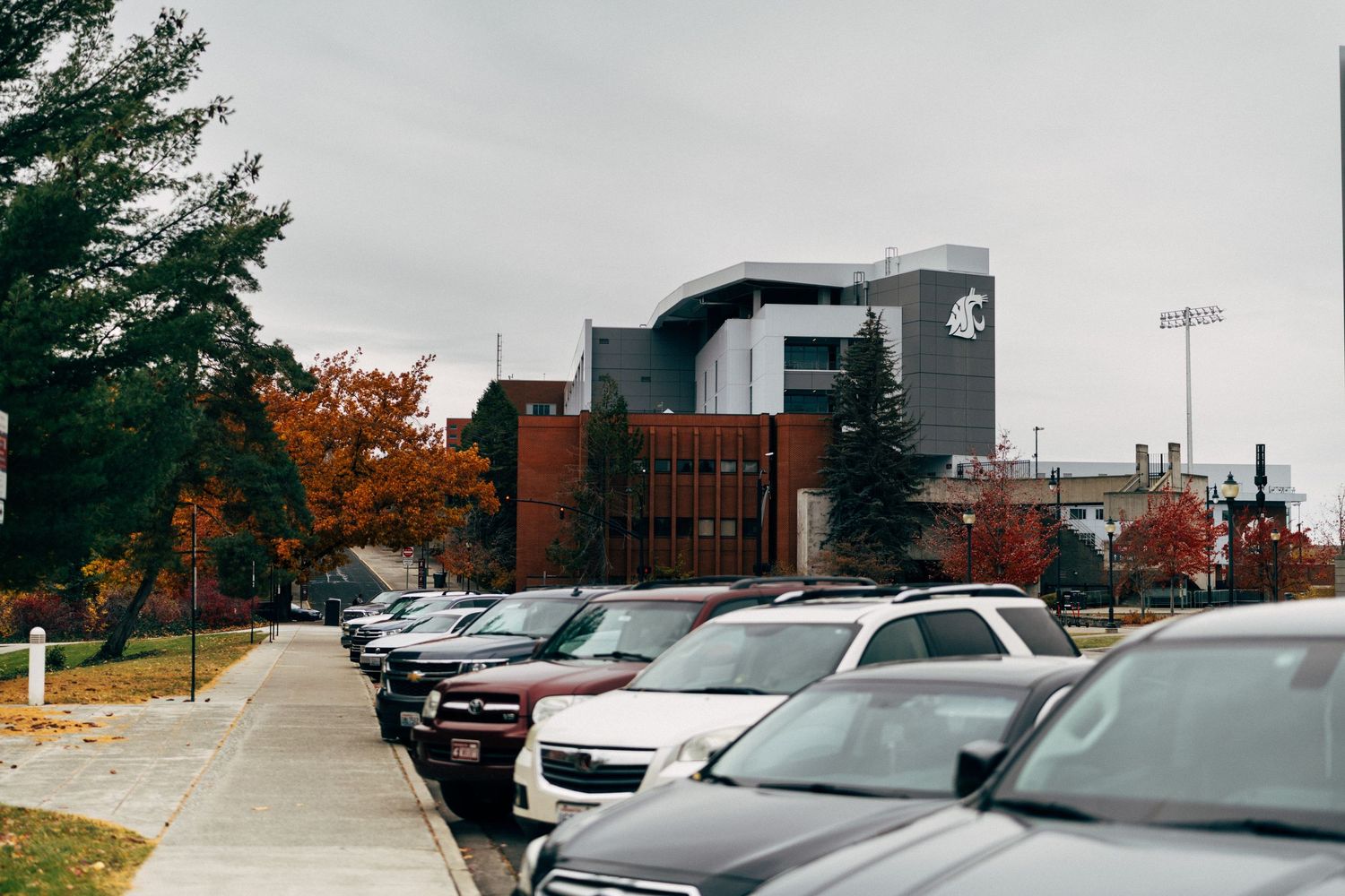Parking lot view with cars and brick buildings in autumn setting.