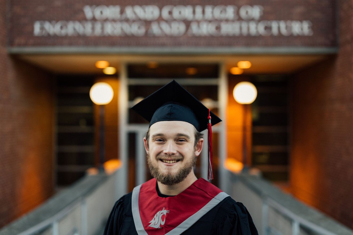 Graduate posing in front of Voiland College building entrance.