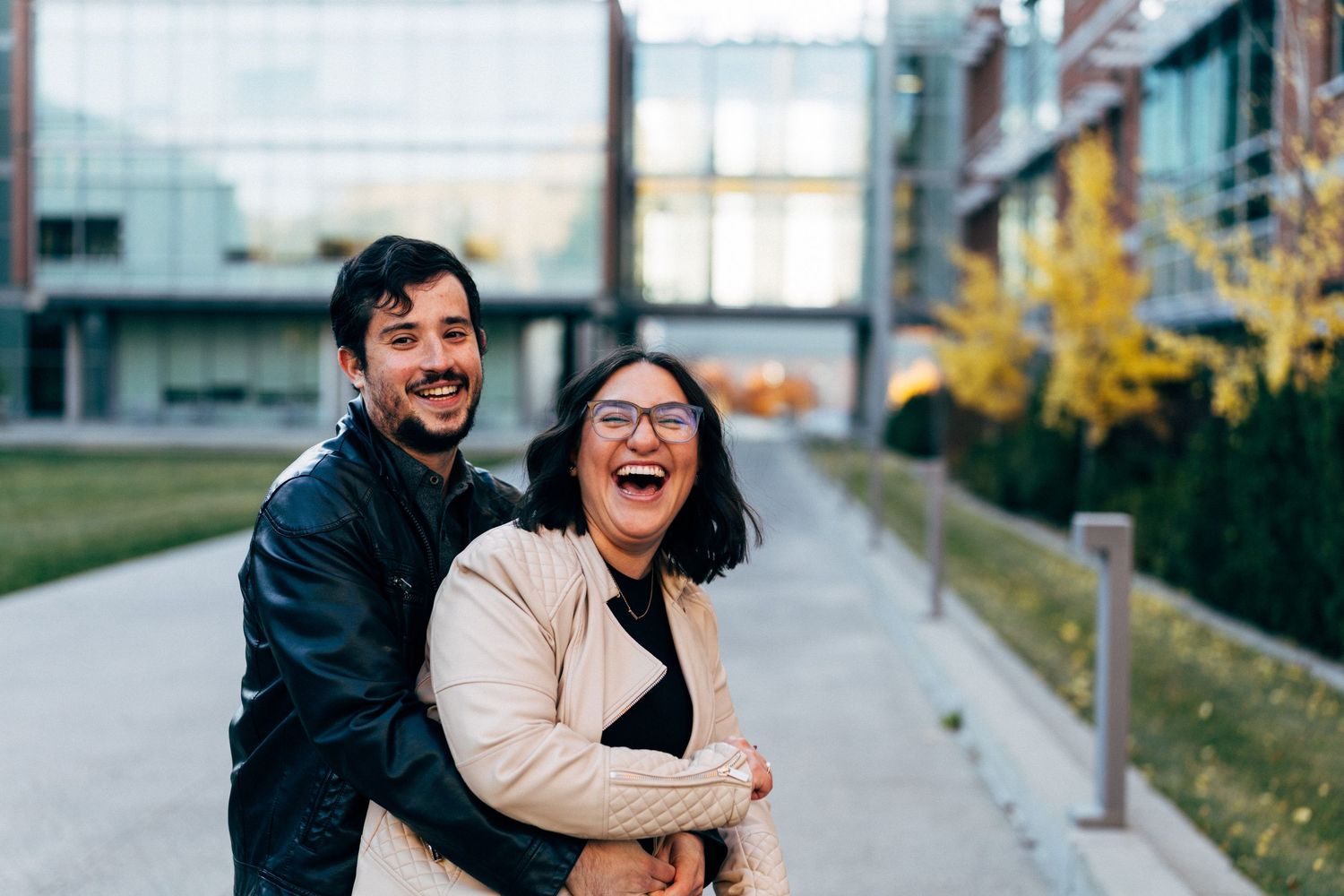 Couple embracing and laughing together on urban pathway during autumn.