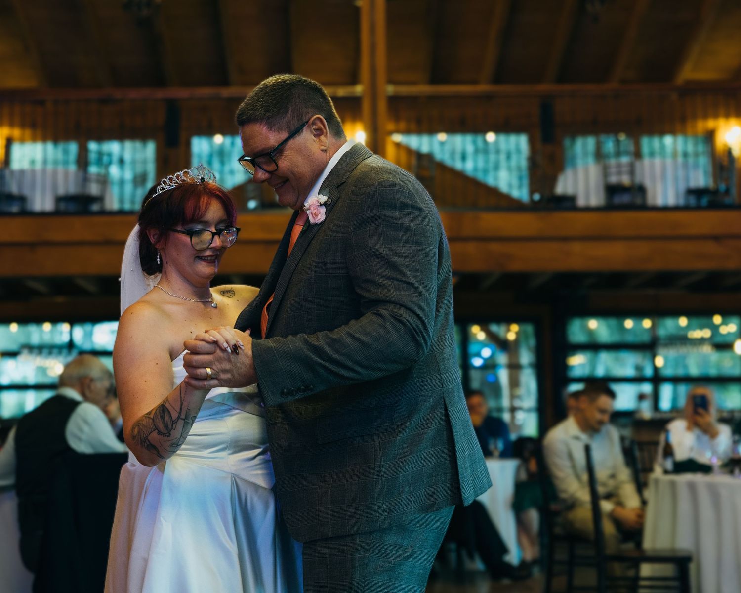 Bride and groom share first dance at wedding reception in rustic venue, exchanging rings and smiling joyfully.