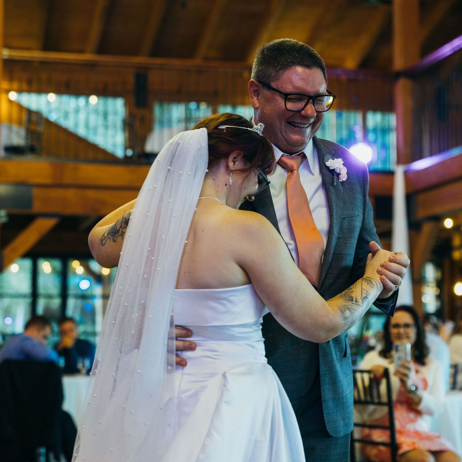 Bride and groom share a joyful first dance at rustic wedding reception venue.