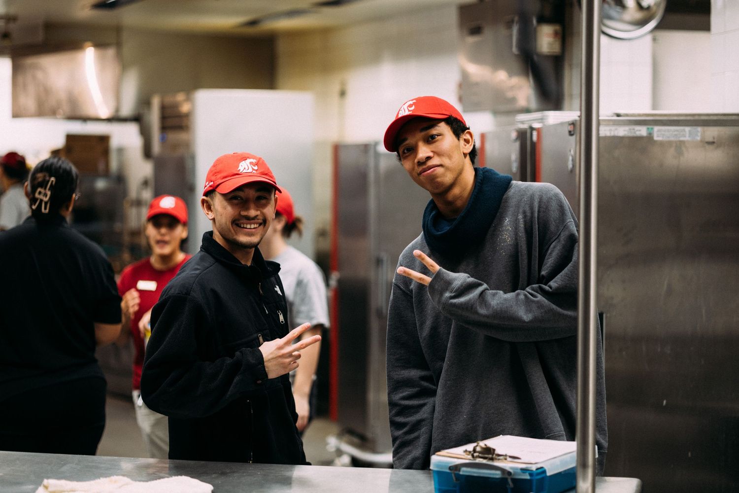 Staff members in red caps working together in a commercial kitchen environment.