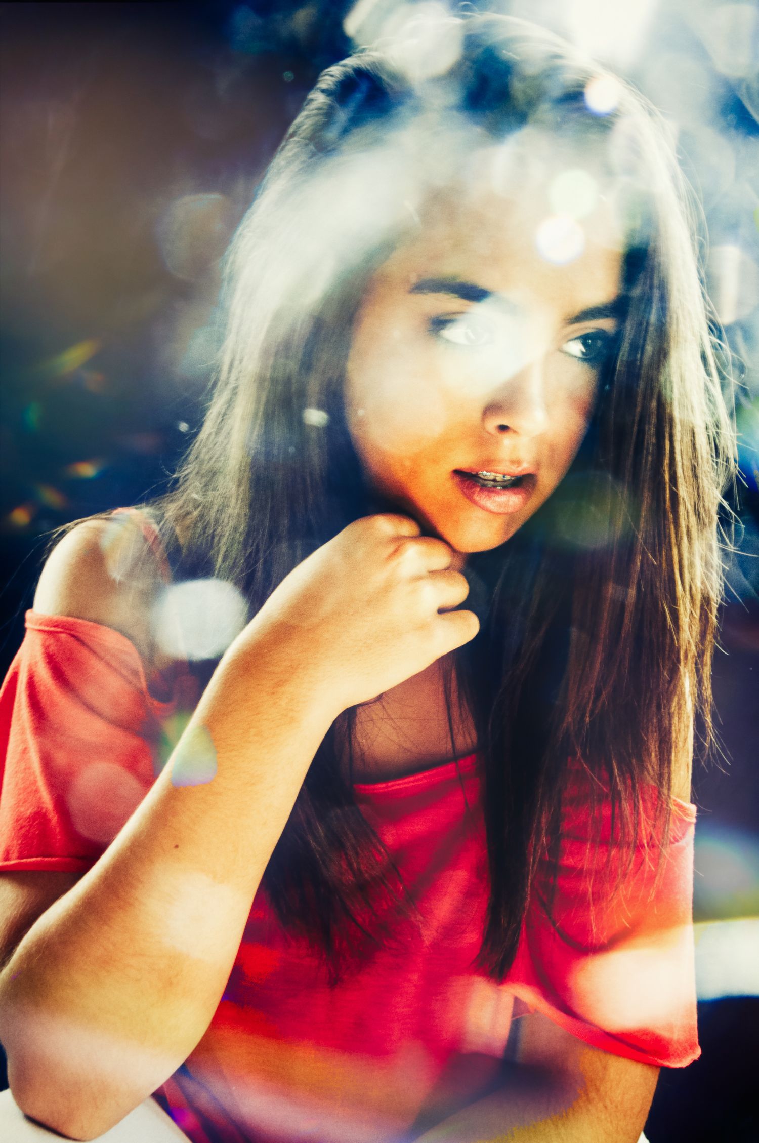 Young woman in red top with bokeh light effects in an artistic portrait photo.