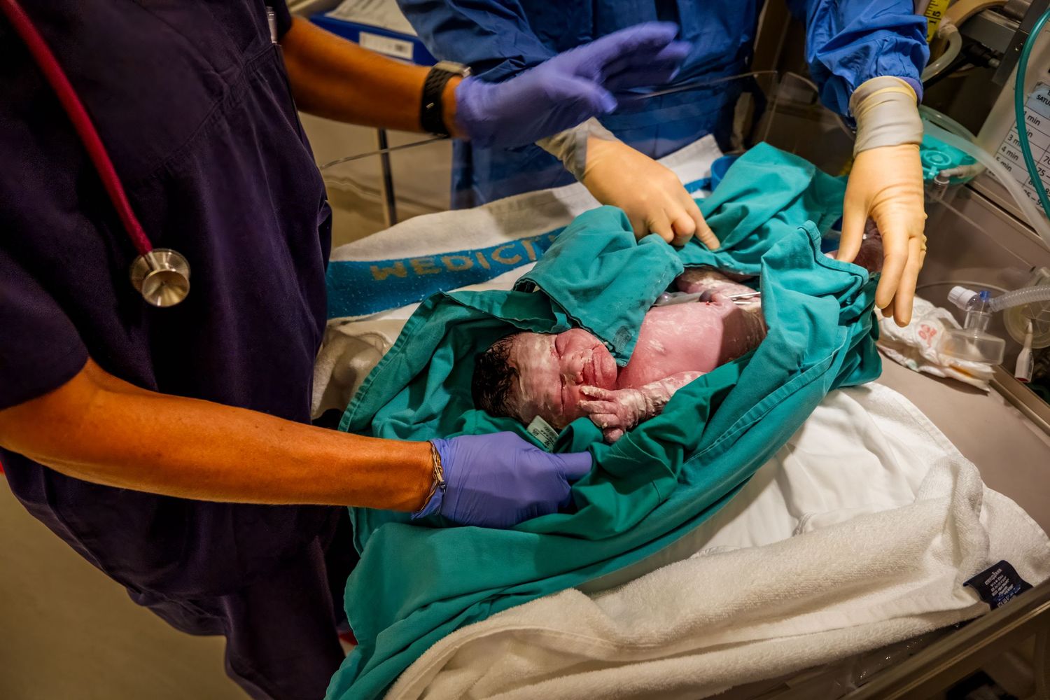 Medical staff handling a newborn baby immediately after birth in a hospital delivery room.