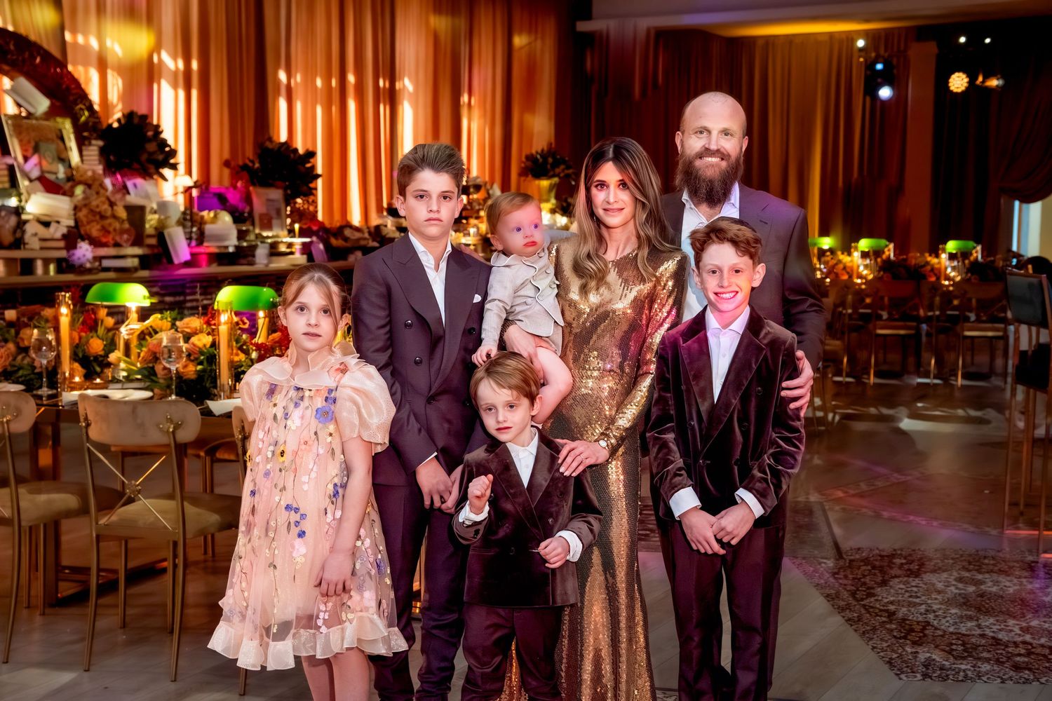 Family of seven posing elegantly at a formal event in a beautifully decorated venue.