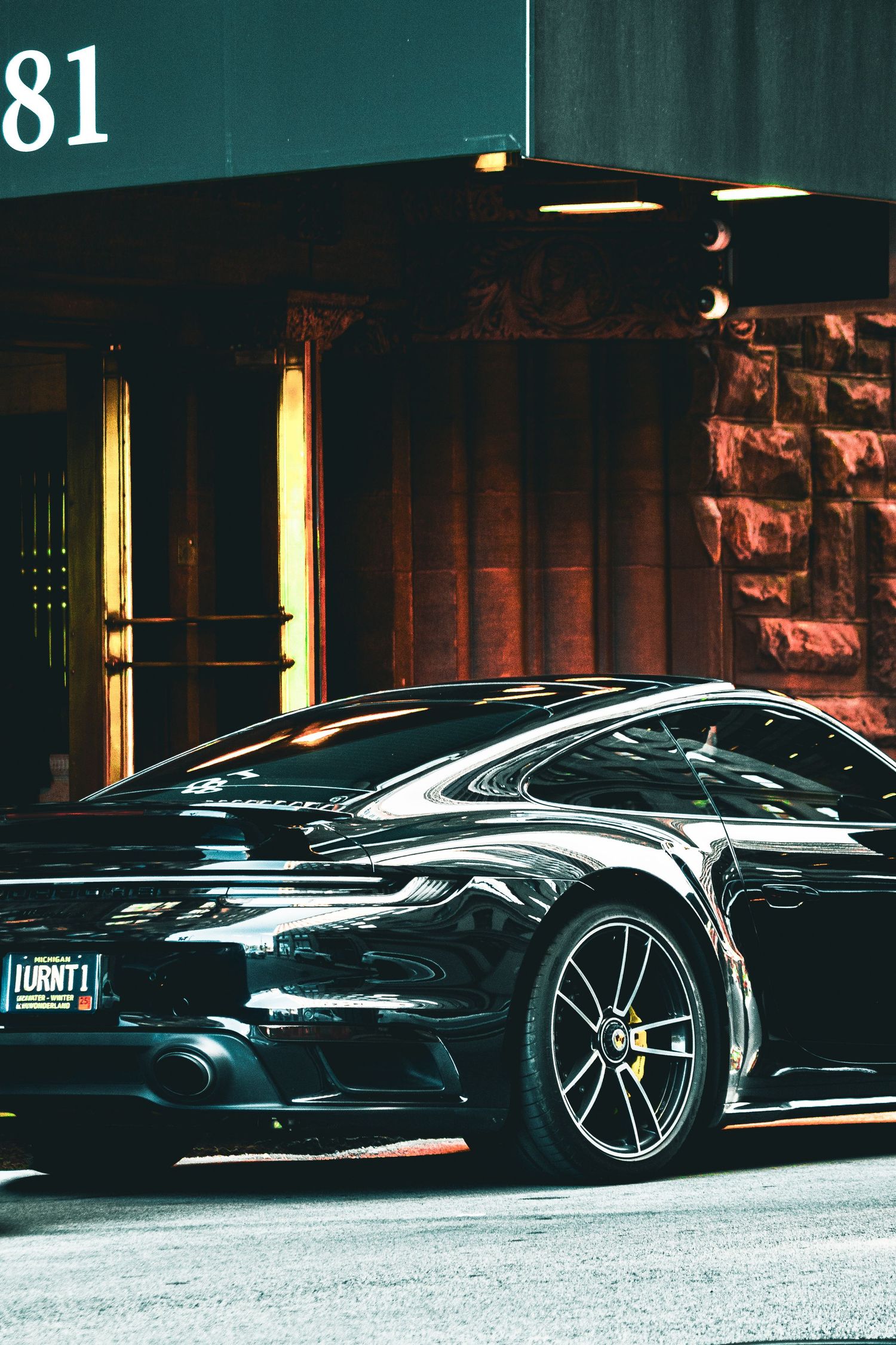Dark luxury sports cars lined up outside building with dramatic evening lighting.