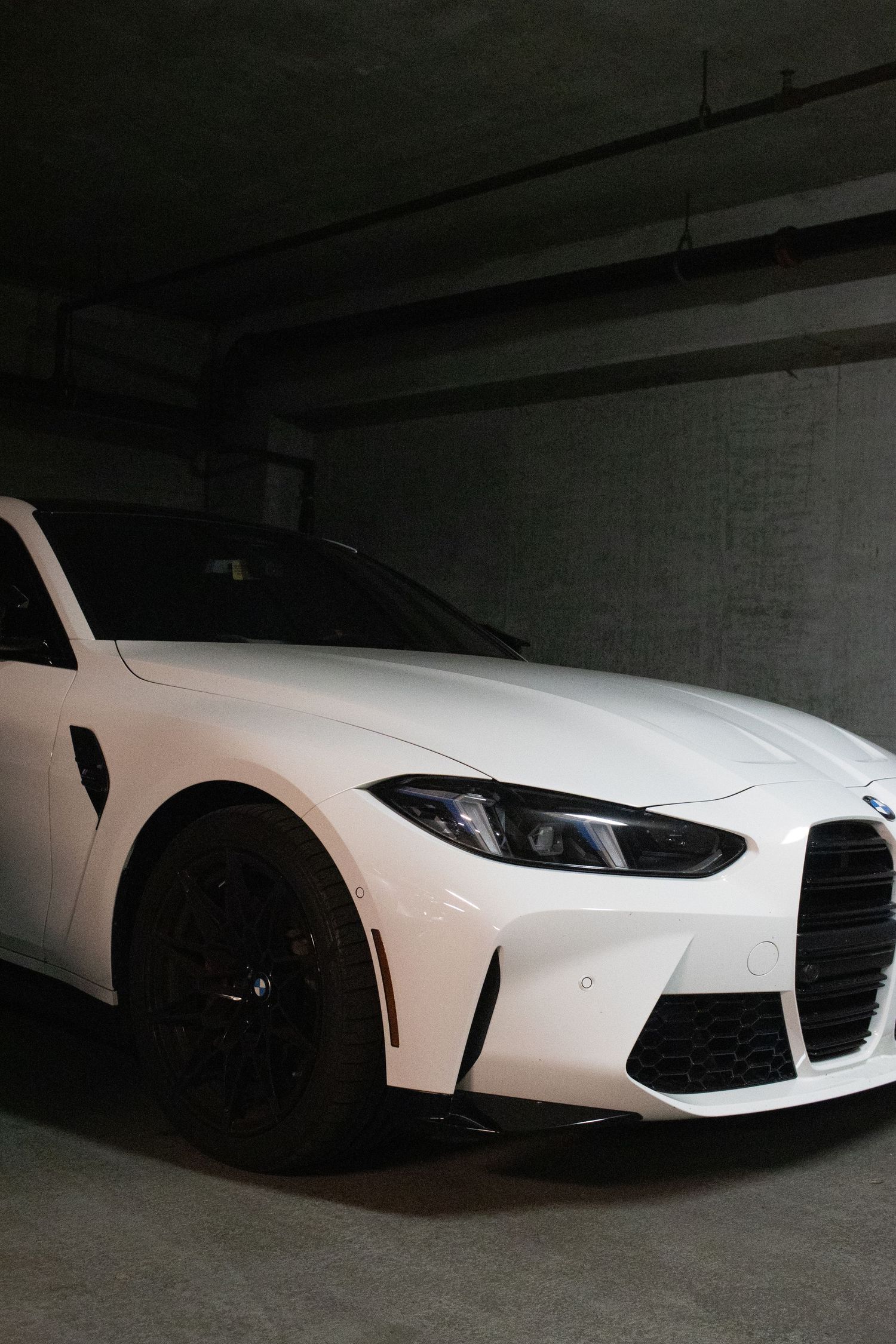 White luxury sports car photographed in dimly lit parking garage.