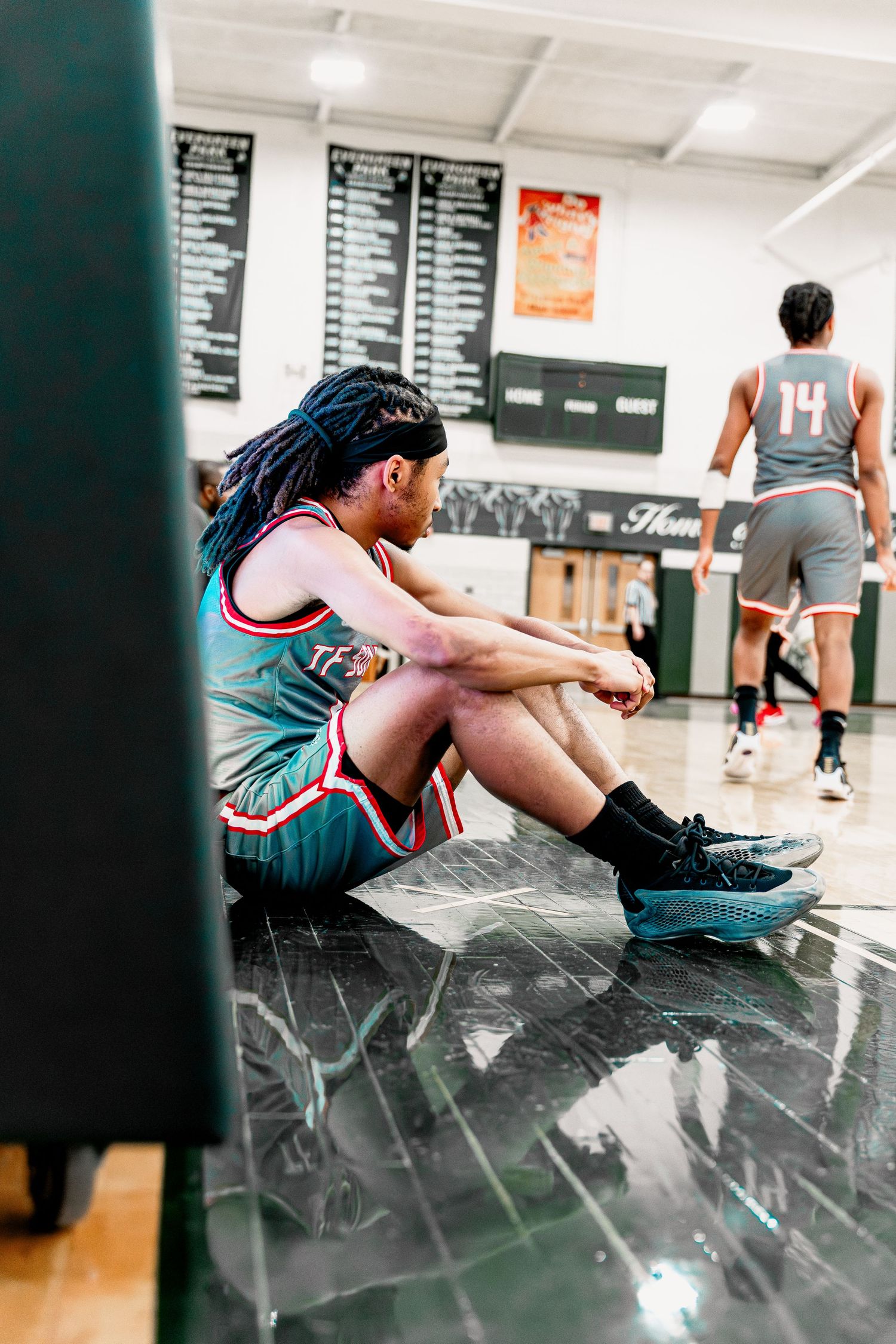 Athletes stretch and warm up on a shiny gym floor before their workout session.
