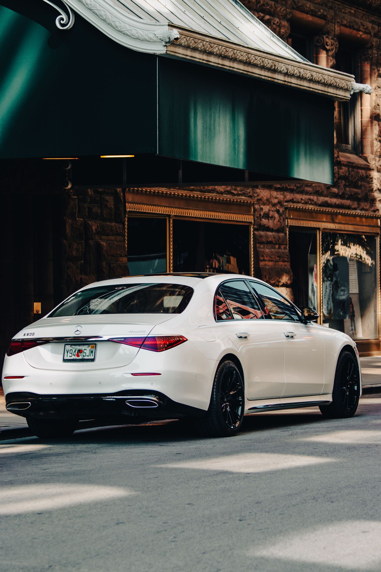 White luxury sedan parked on street outside historic stone building.