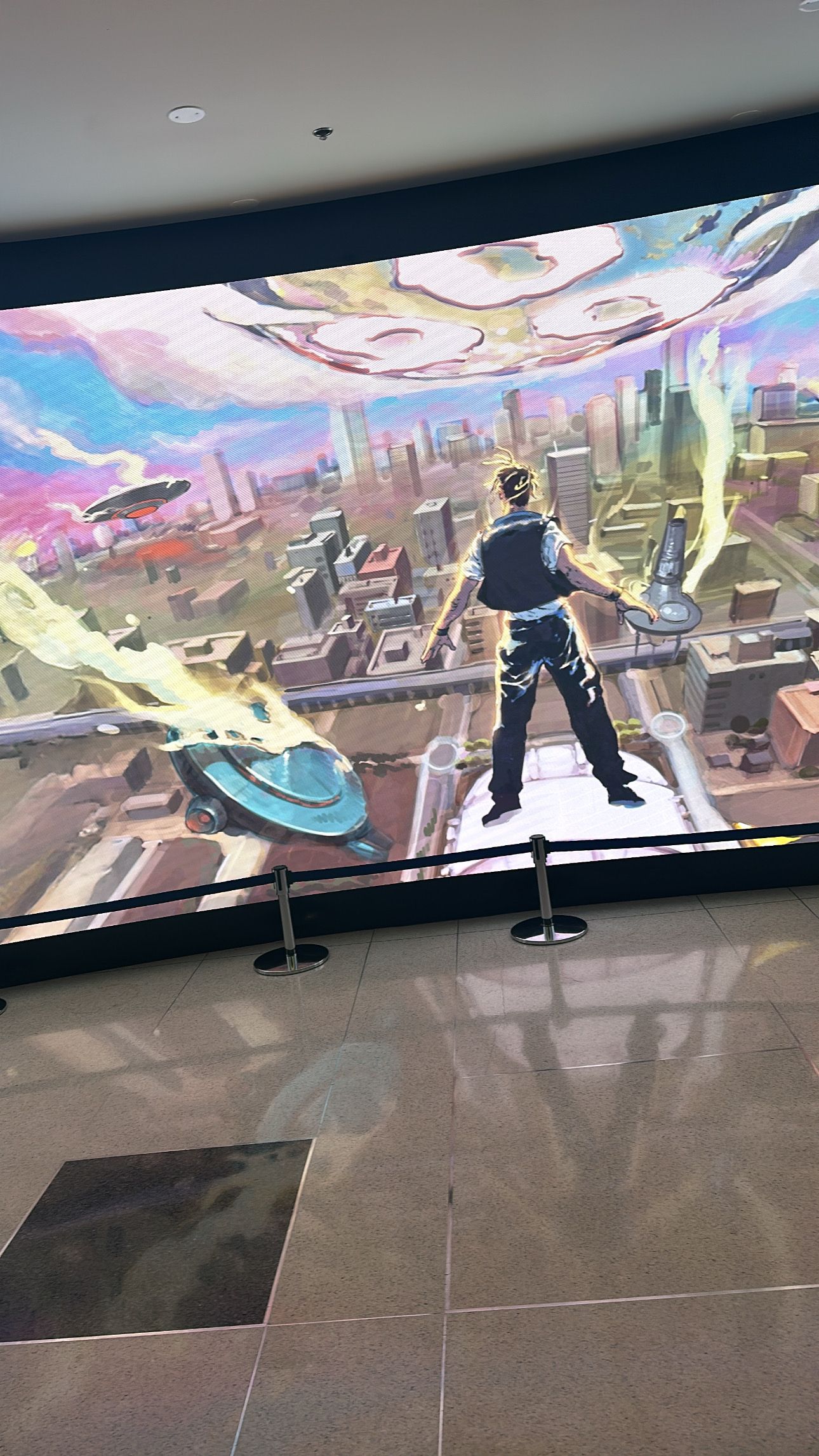 A panoramic digital display showing an animated cityscape with silhouetted figures against a colorful futuristic background.
