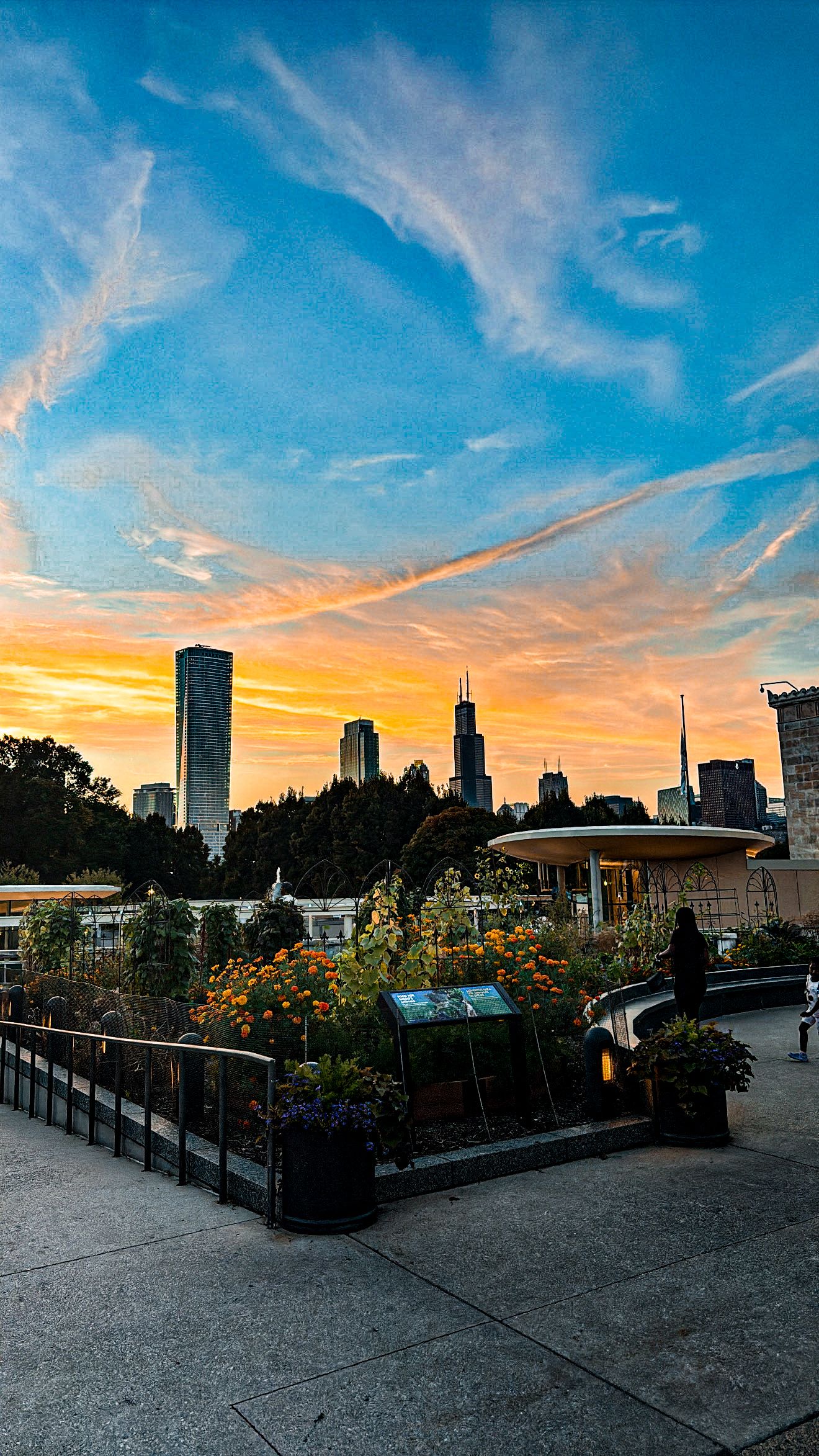 Panoramic cityscape view of Minneapolis skyline at sunset with dramatic orange and blue sky from rooftop garden.