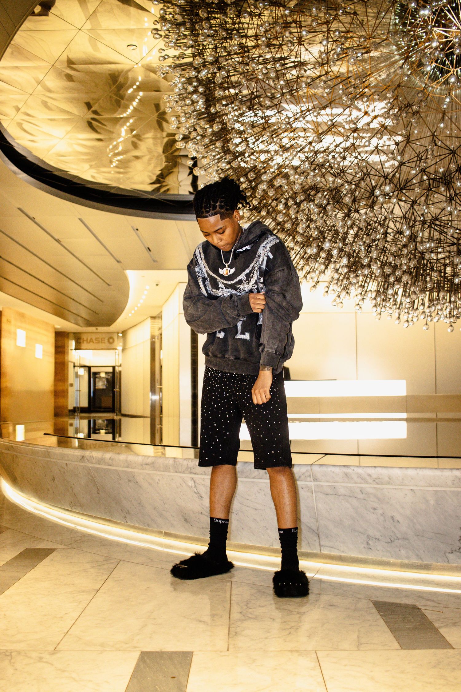 Person in black clothing standing on reflective floor under decorative lighting in modern interior space.