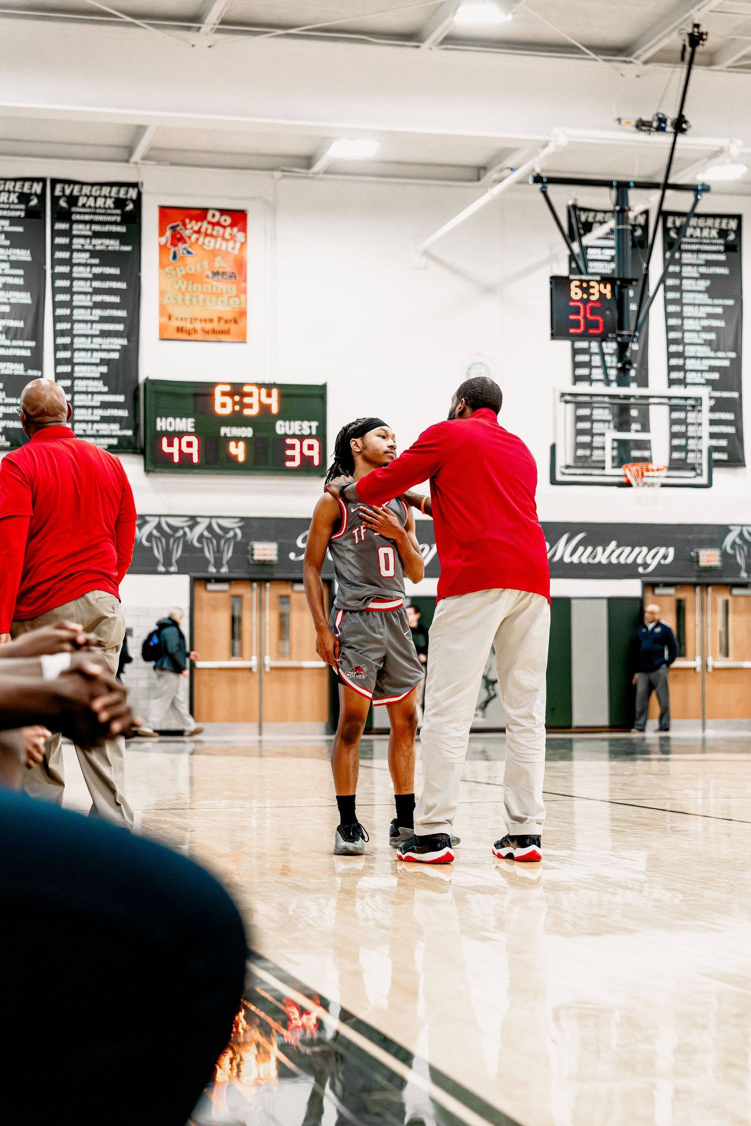 Basketball players compete in a gym with scoreboard displays and white walls showing various game statistics.