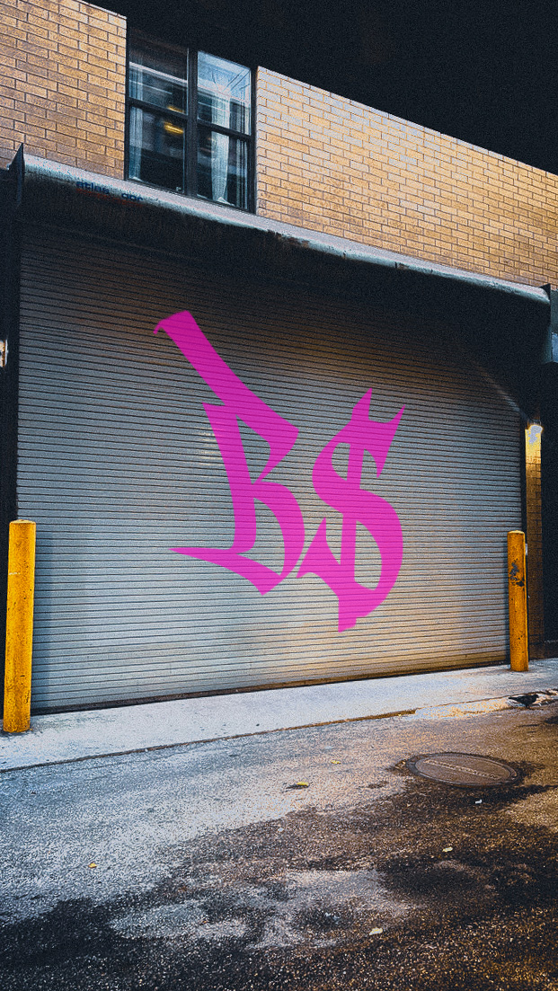 Pink graffiti tag on metal garage door with brick wall above in urban setting.