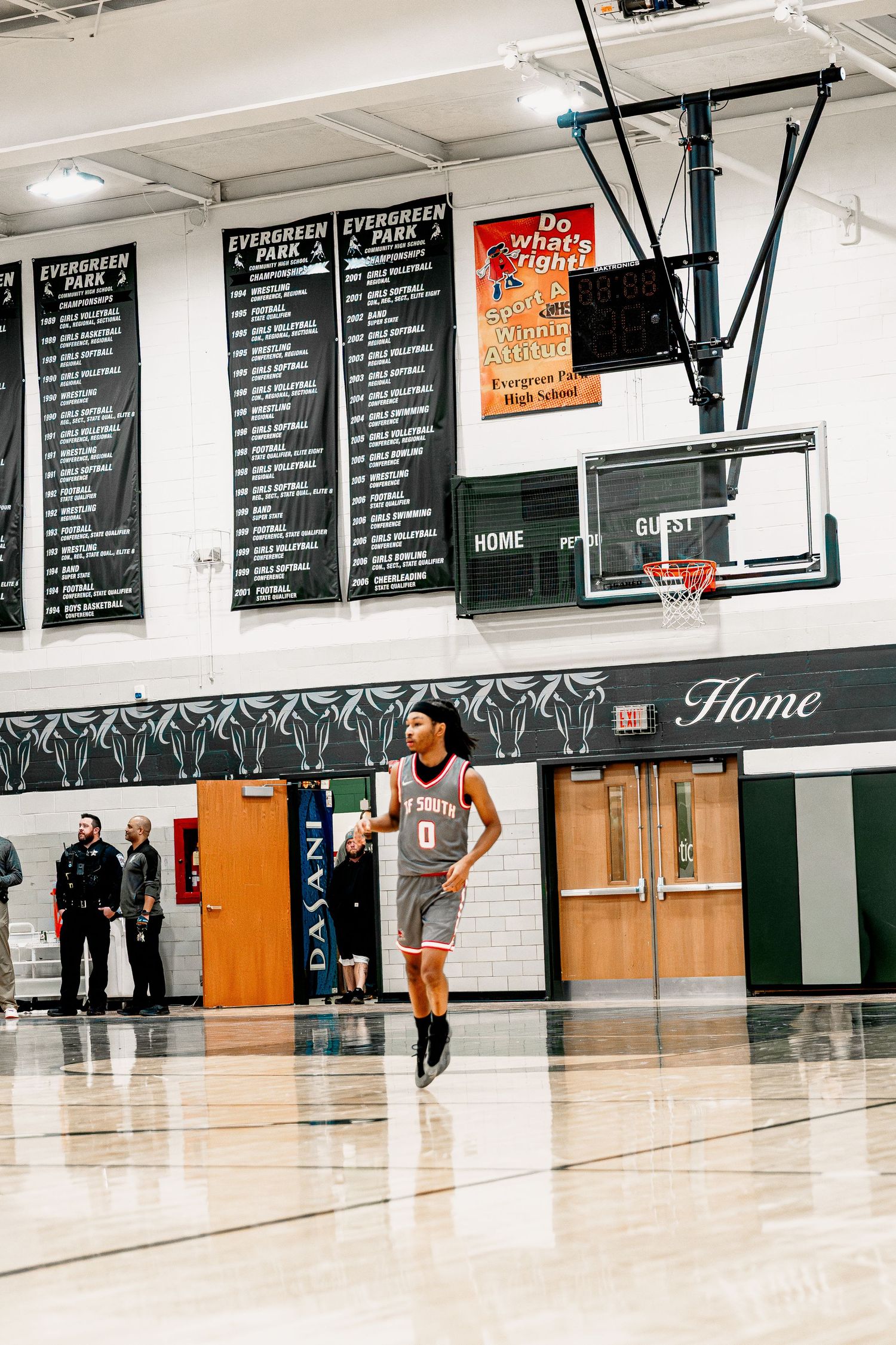 Basketball player takes a free throw shot in a high school gymnasium with championship banners on the wall.