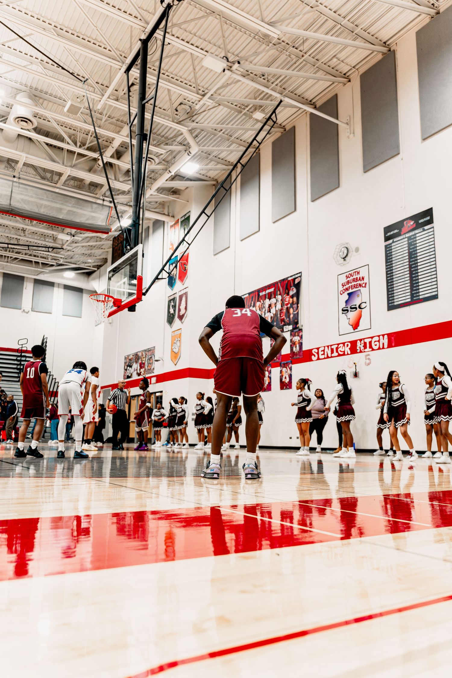 Basketball players practicing in a modern gymnasium with red floor markings and white walls during training session.