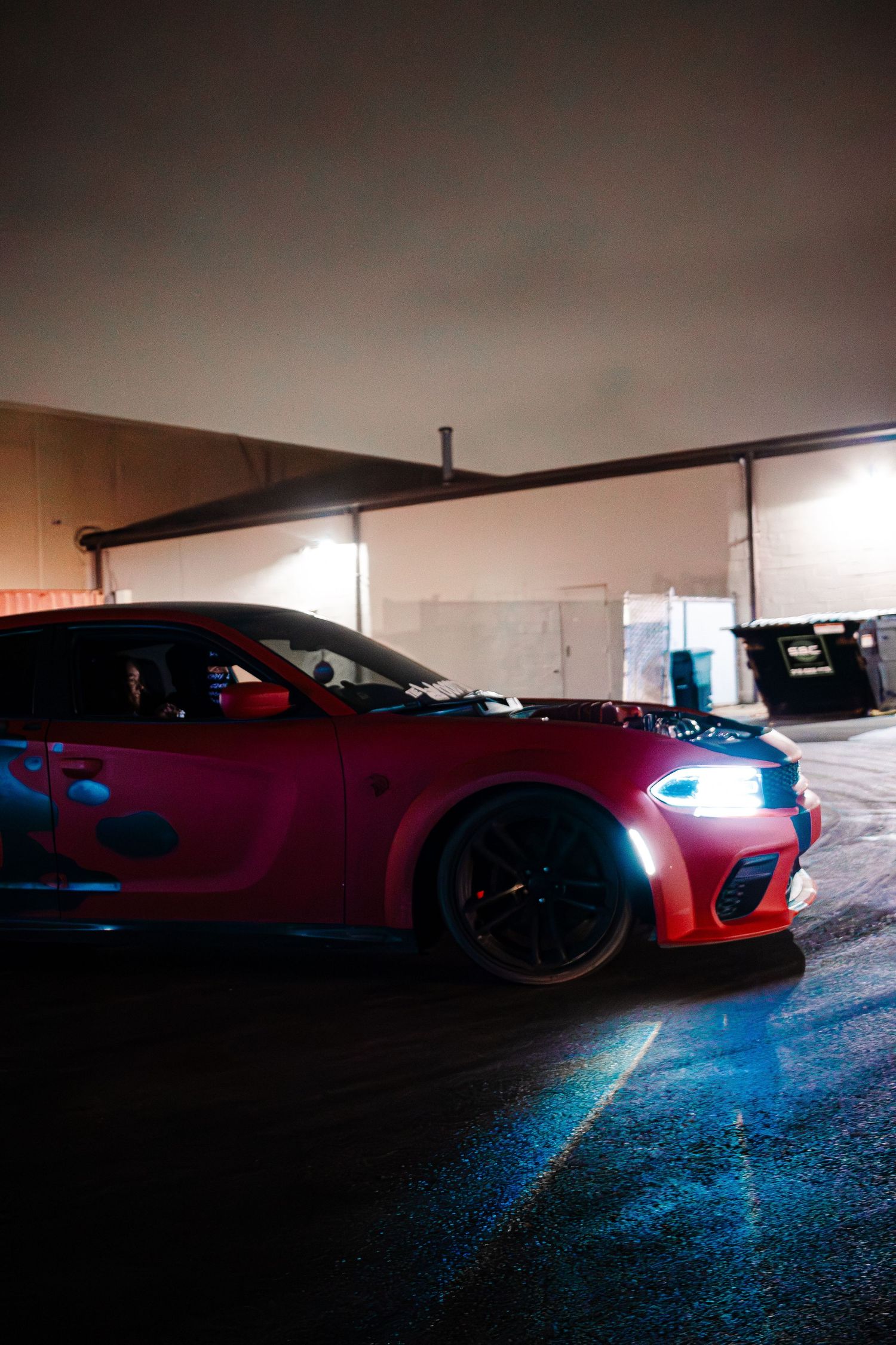 Red sports car with custom modifications and glowing lights parked in dimly lit garage.