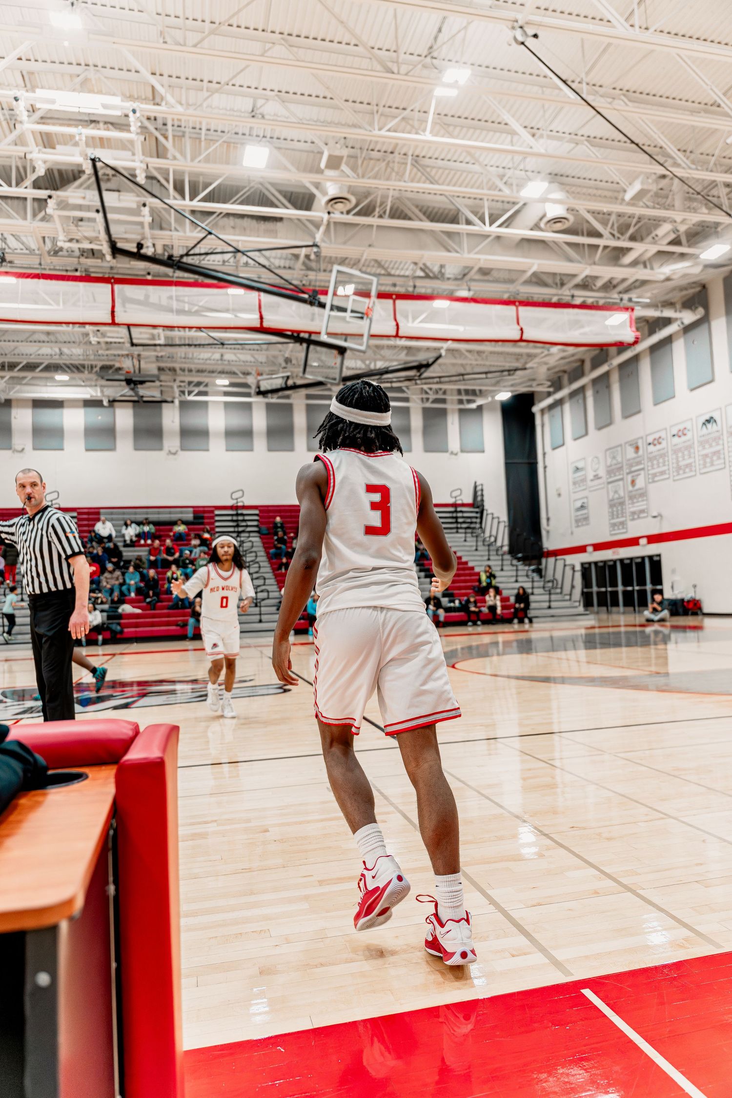 Players practicing basketball moves on a polished gymnasium floor with red accents.