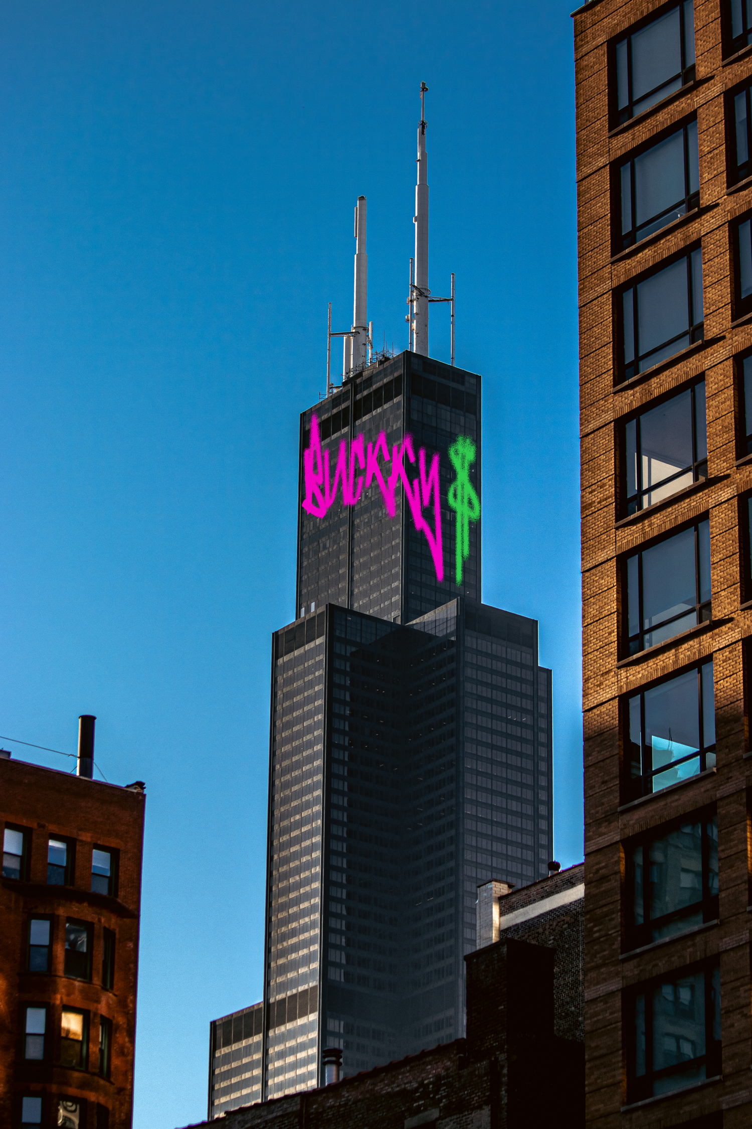 Willis Tower silhouette against blue sky with colorful neon signage.