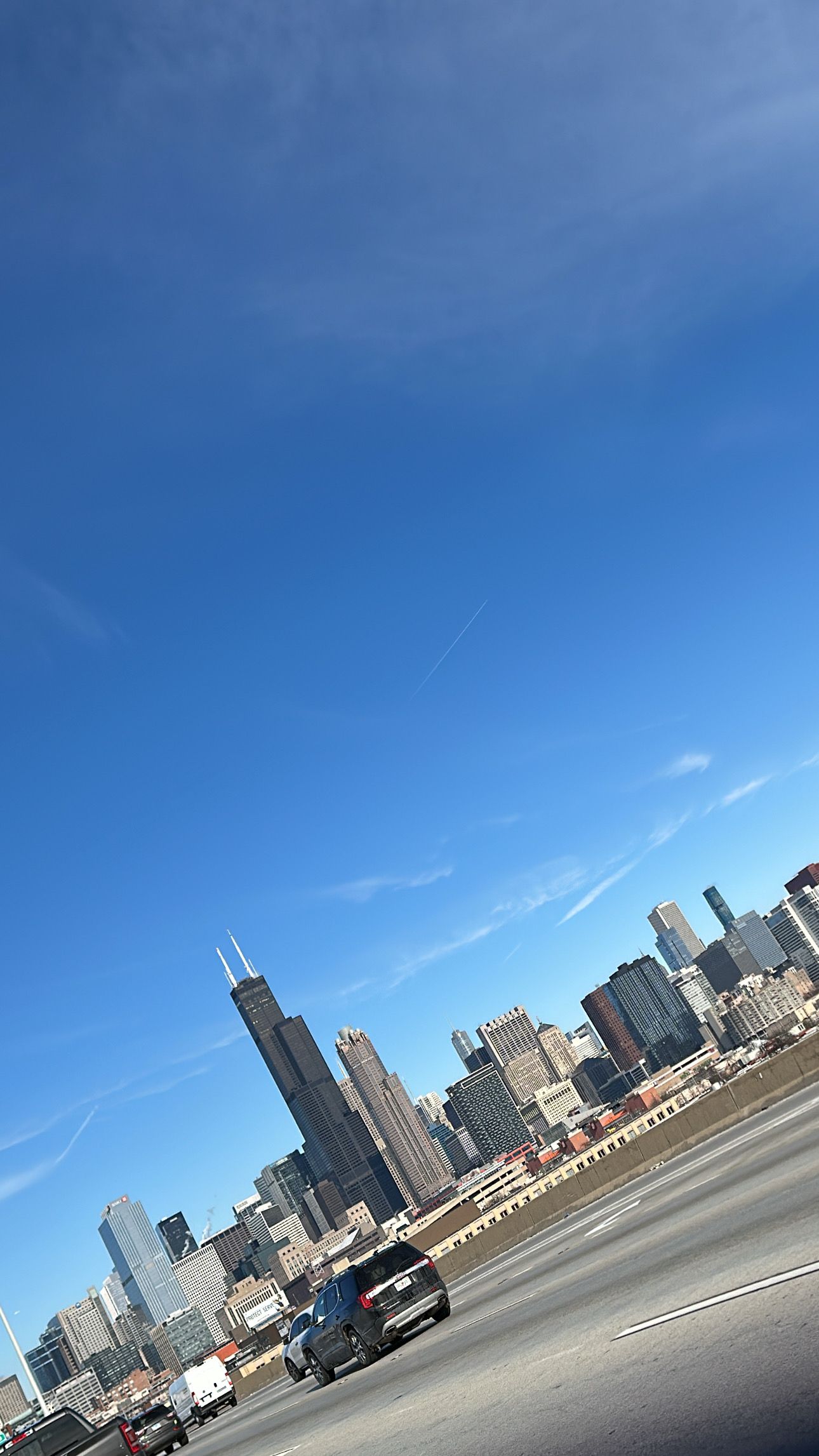 Chicago skyline view from Lake Shore Drive with skyscrapers against bright blue sky on sunny day.