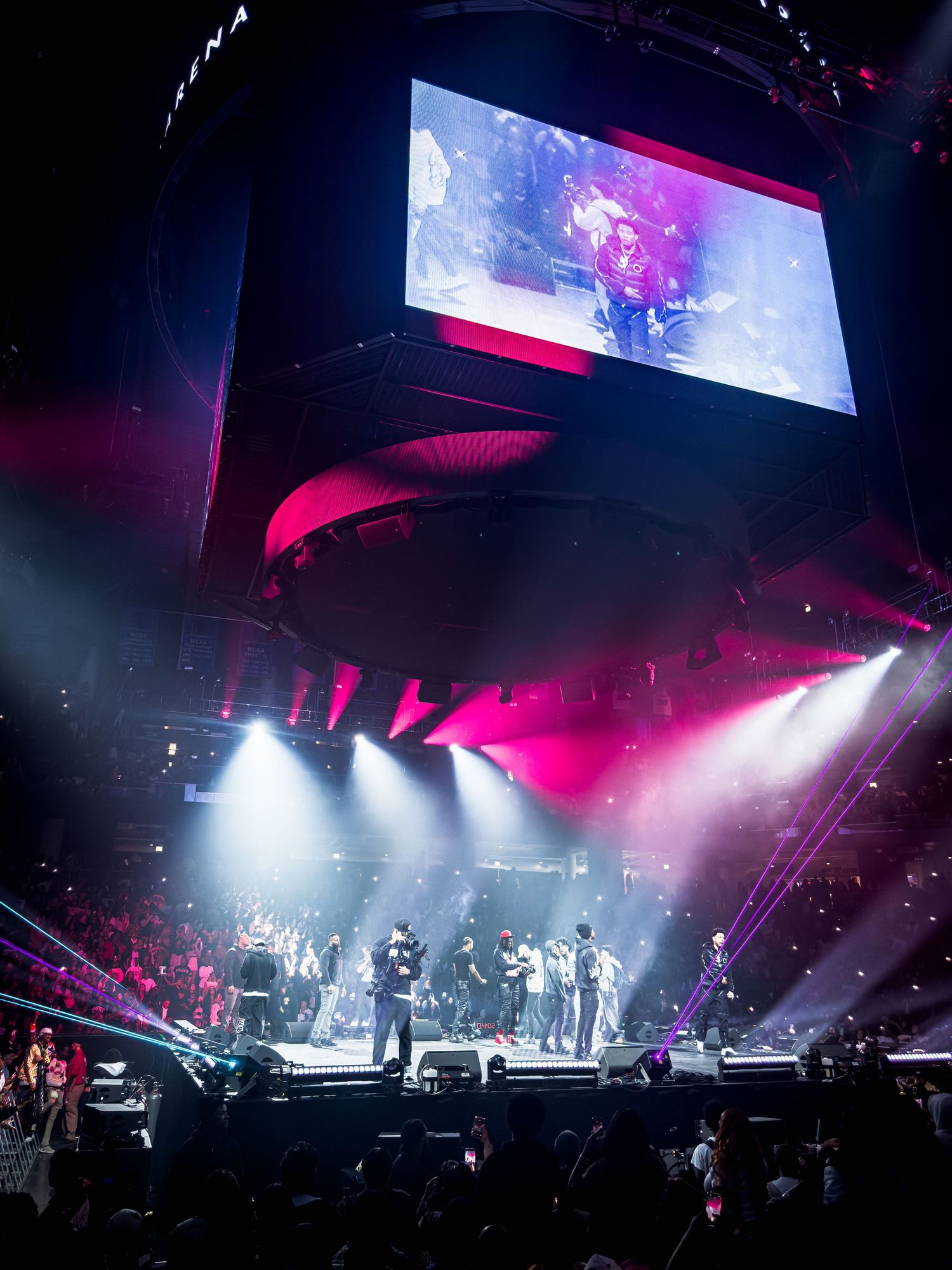 Concert stage illuminated with dramatic pink and white lighting effects during a live performance in an arena setting.
