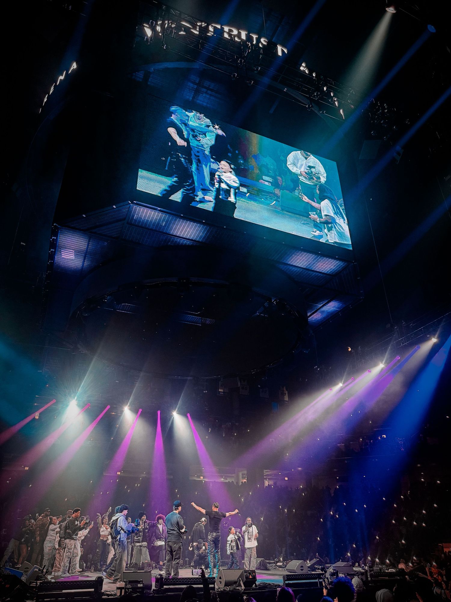 Concert stage illuminated with dramatic blue and purple lighting effects during a live performance.