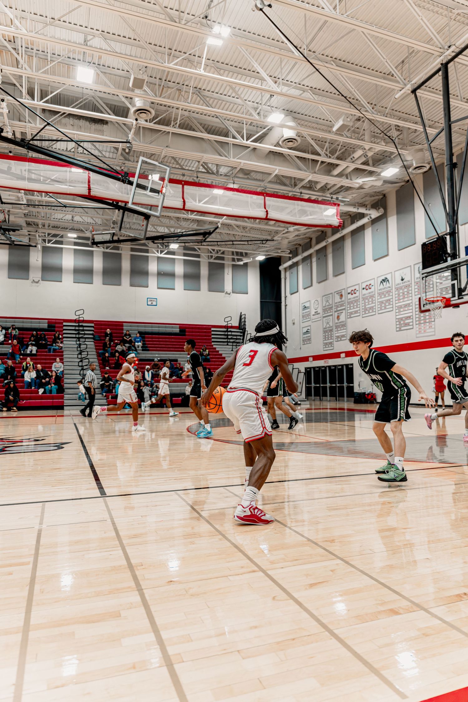 Athletes practice basketball drills on a gleaming indoor court with red and white color scheme.