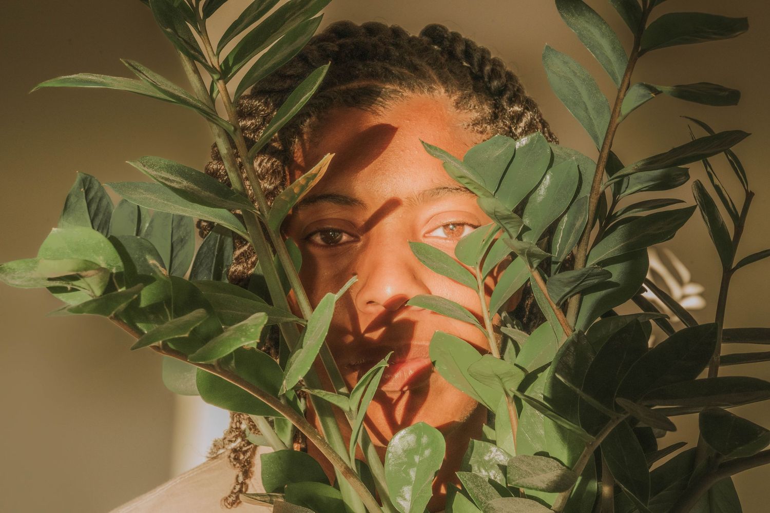 Artistic portrait through green plant leaves creating a natural framed effect.