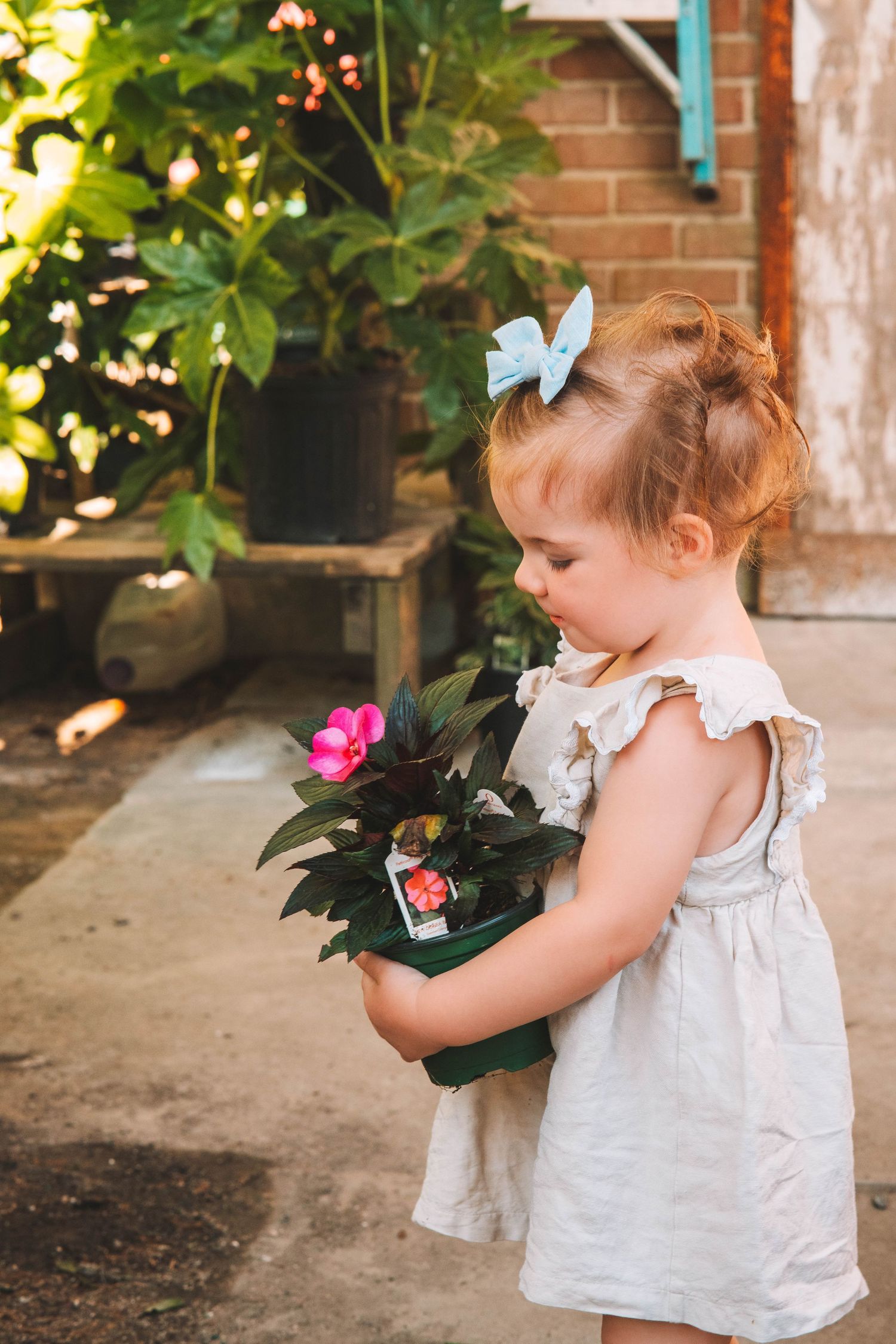 Young child in white dress exploring garden with pink and blue butterfly decorations.