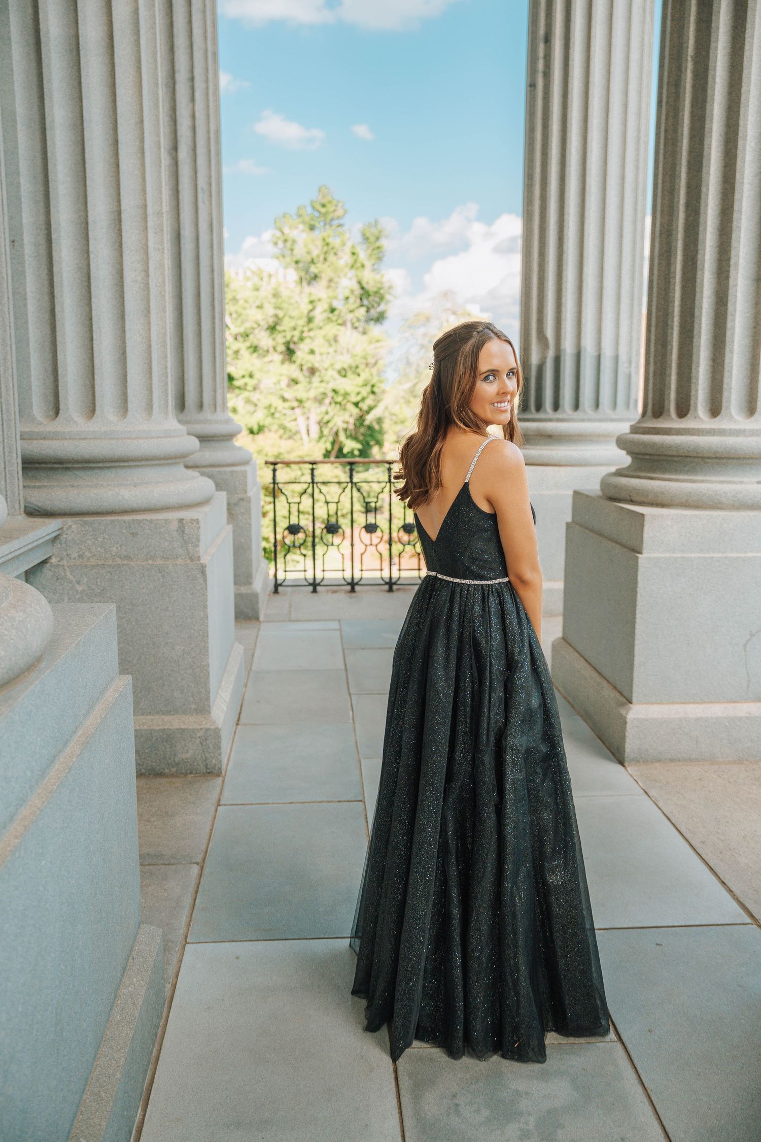 A person in a flowing black evening gown poses elegantly between classical white stone columns in a series of photos.