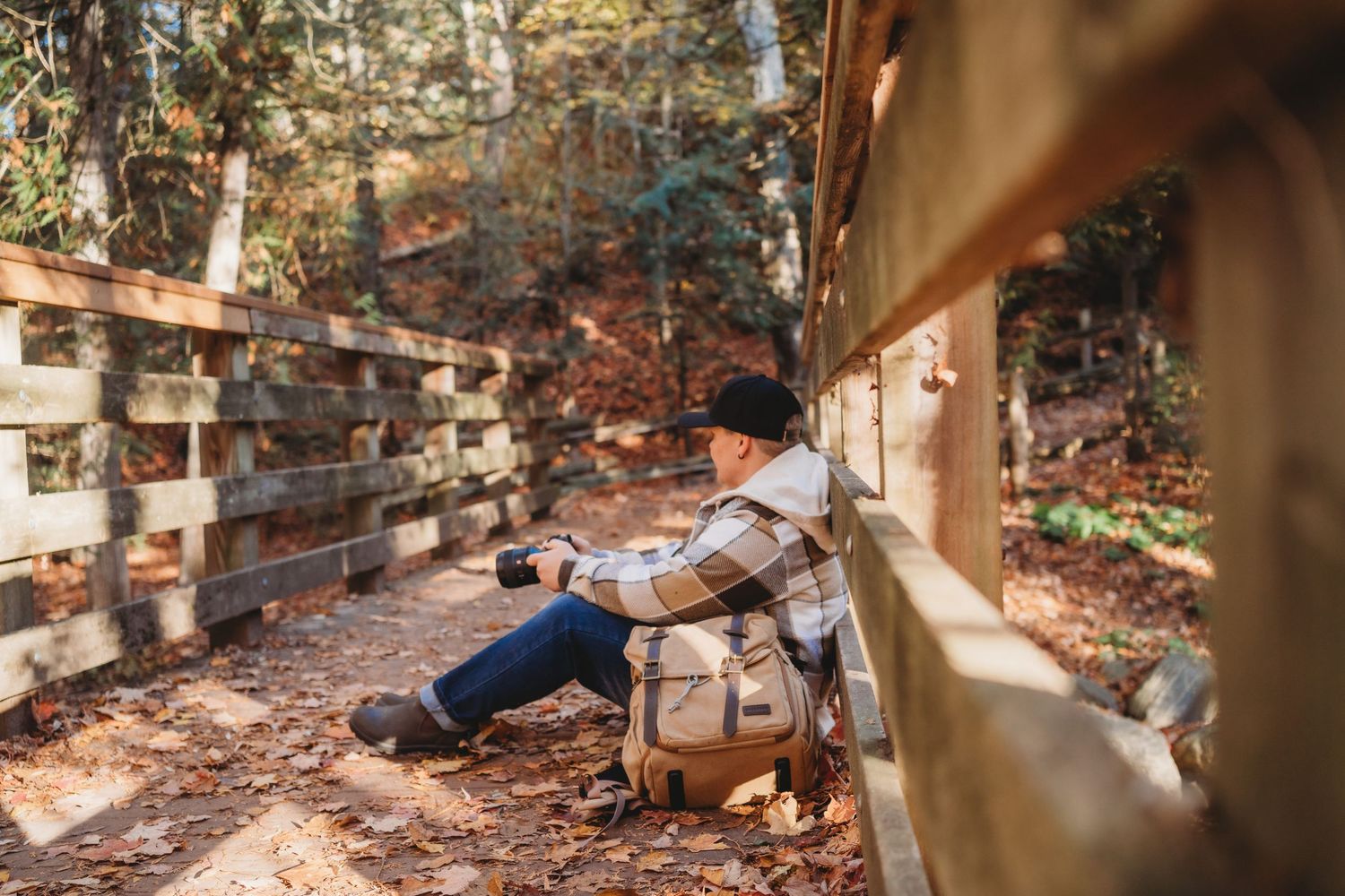 A couple sits together on a wooden bench in a serene forest setting during an engagement photography session.