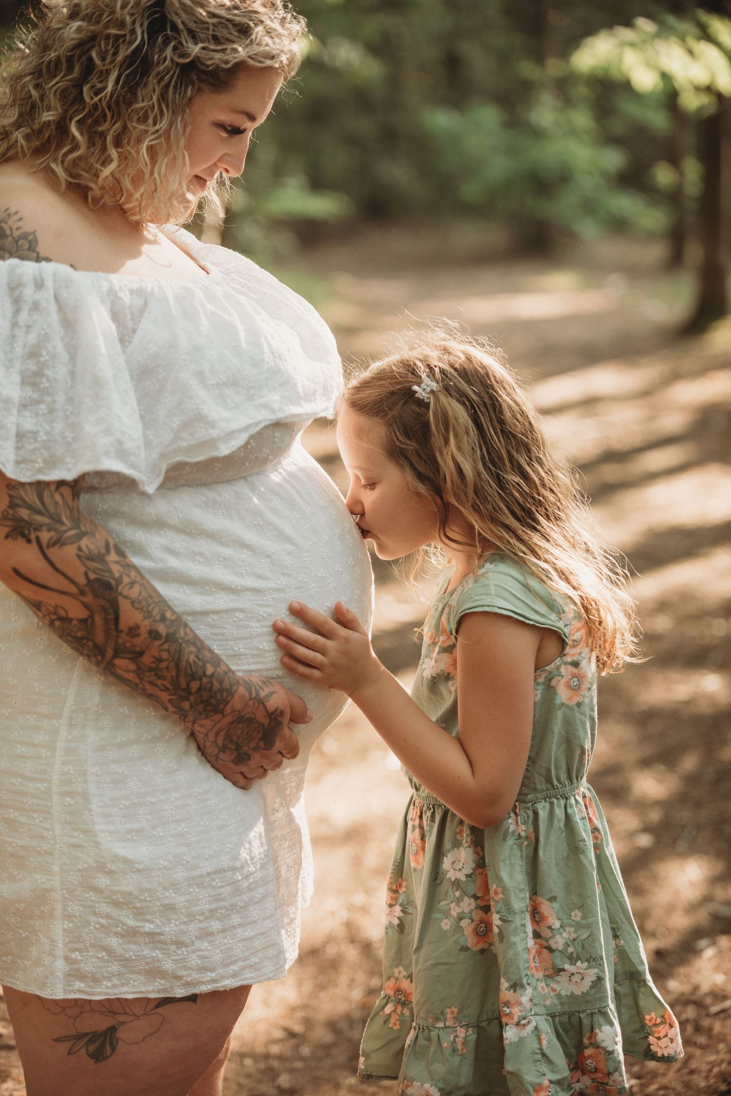 A series of tender moments between a person in white lace and small child in a sage green dress in a sunlit forest setting.